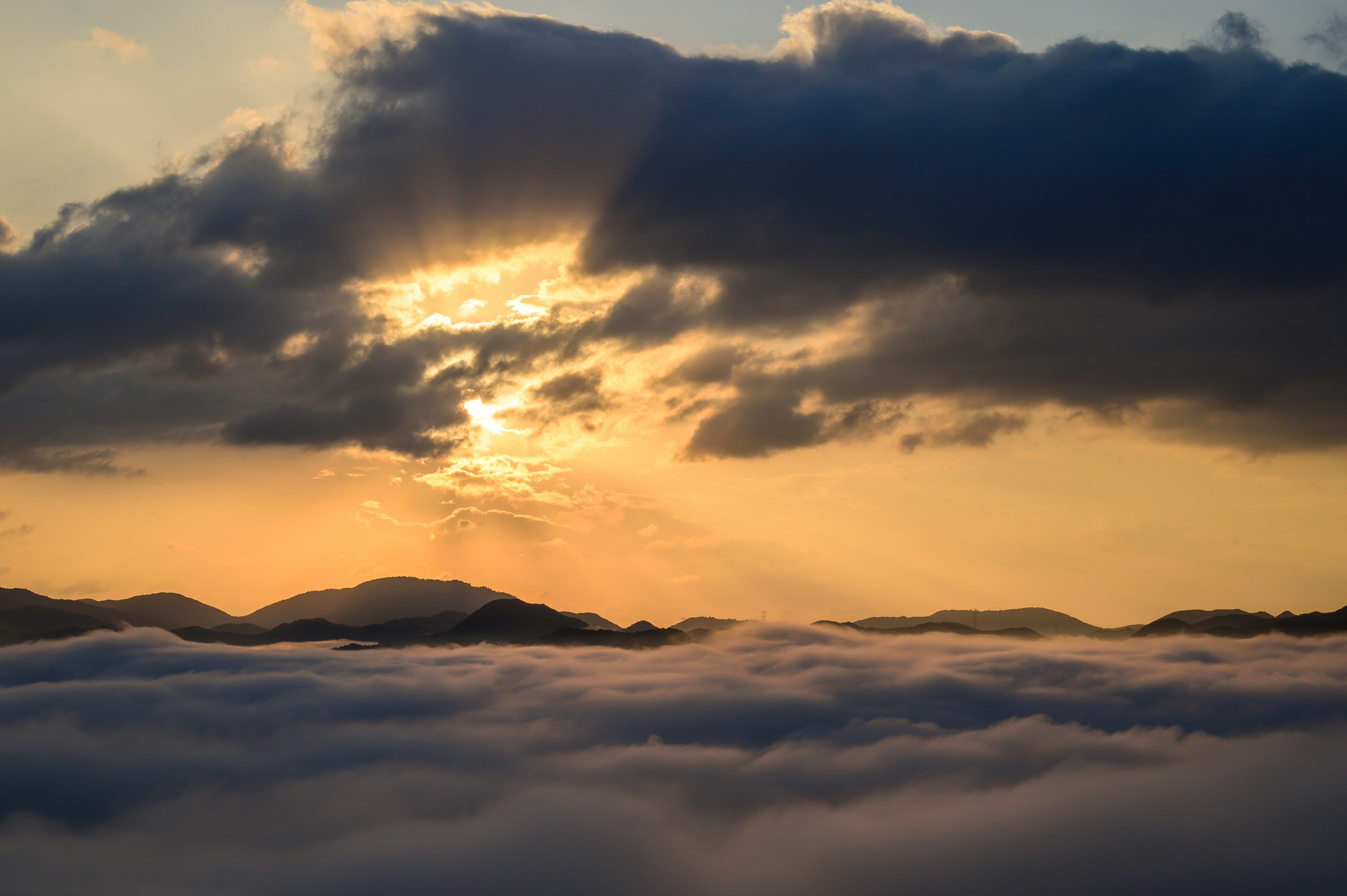 Siluet gunung dengan matahari terbenam di atas lautan awan