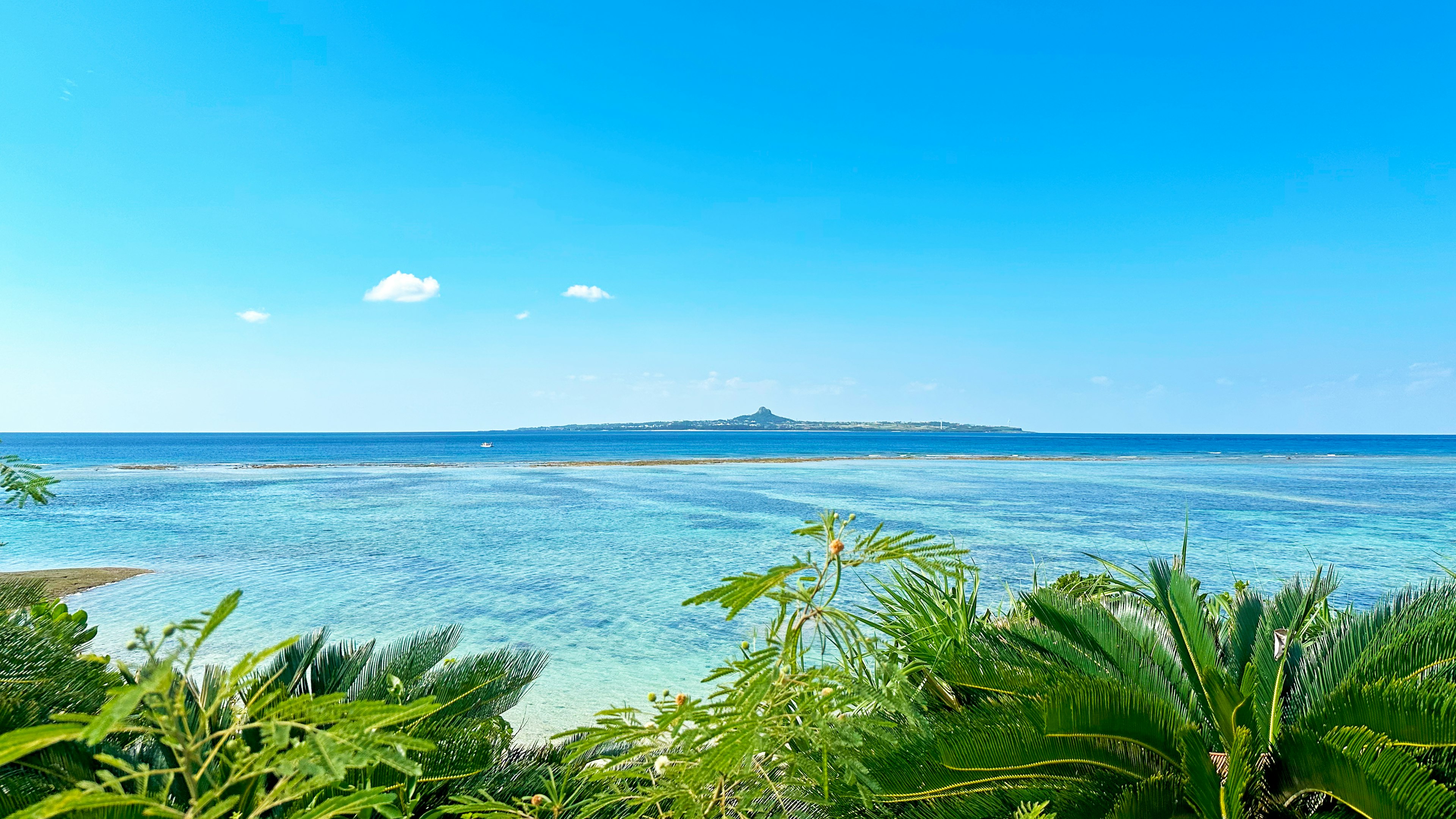 Scenic view of a small island surrounded by blue sea and sky with lush greenery