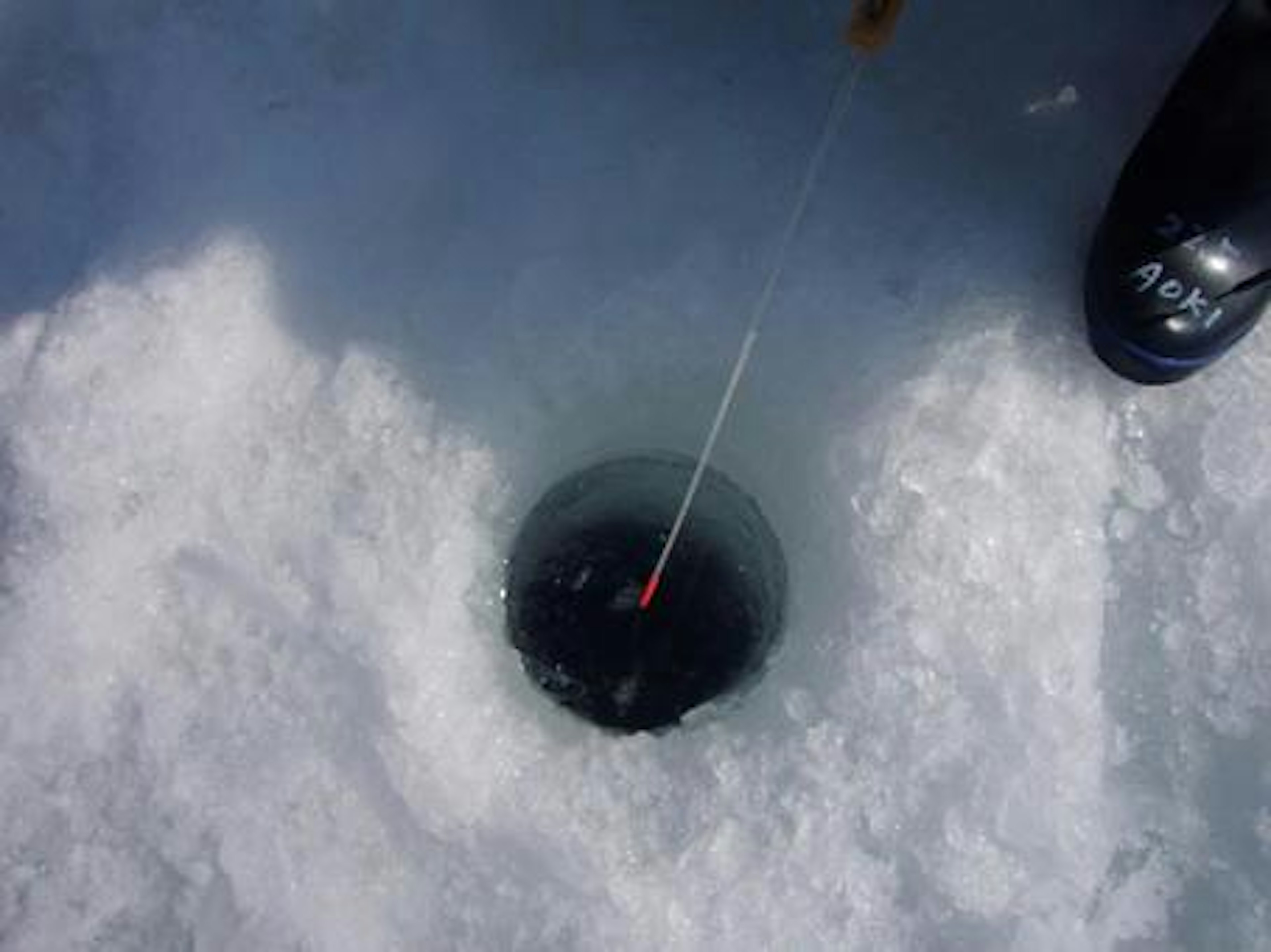 A hole in the ice with fishing line visible