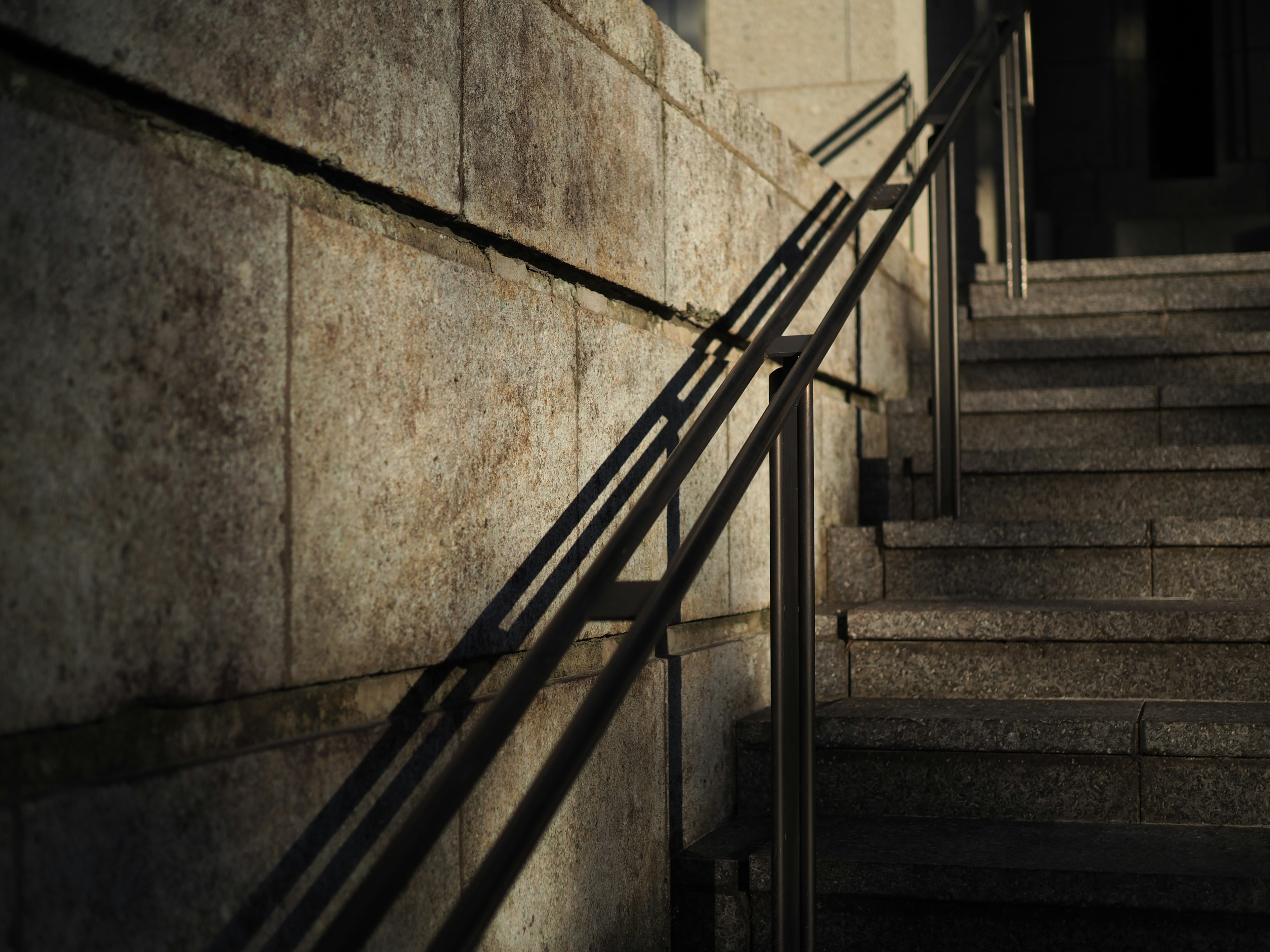 Barandilla de metal proyectando sombras en escaleras de piedra