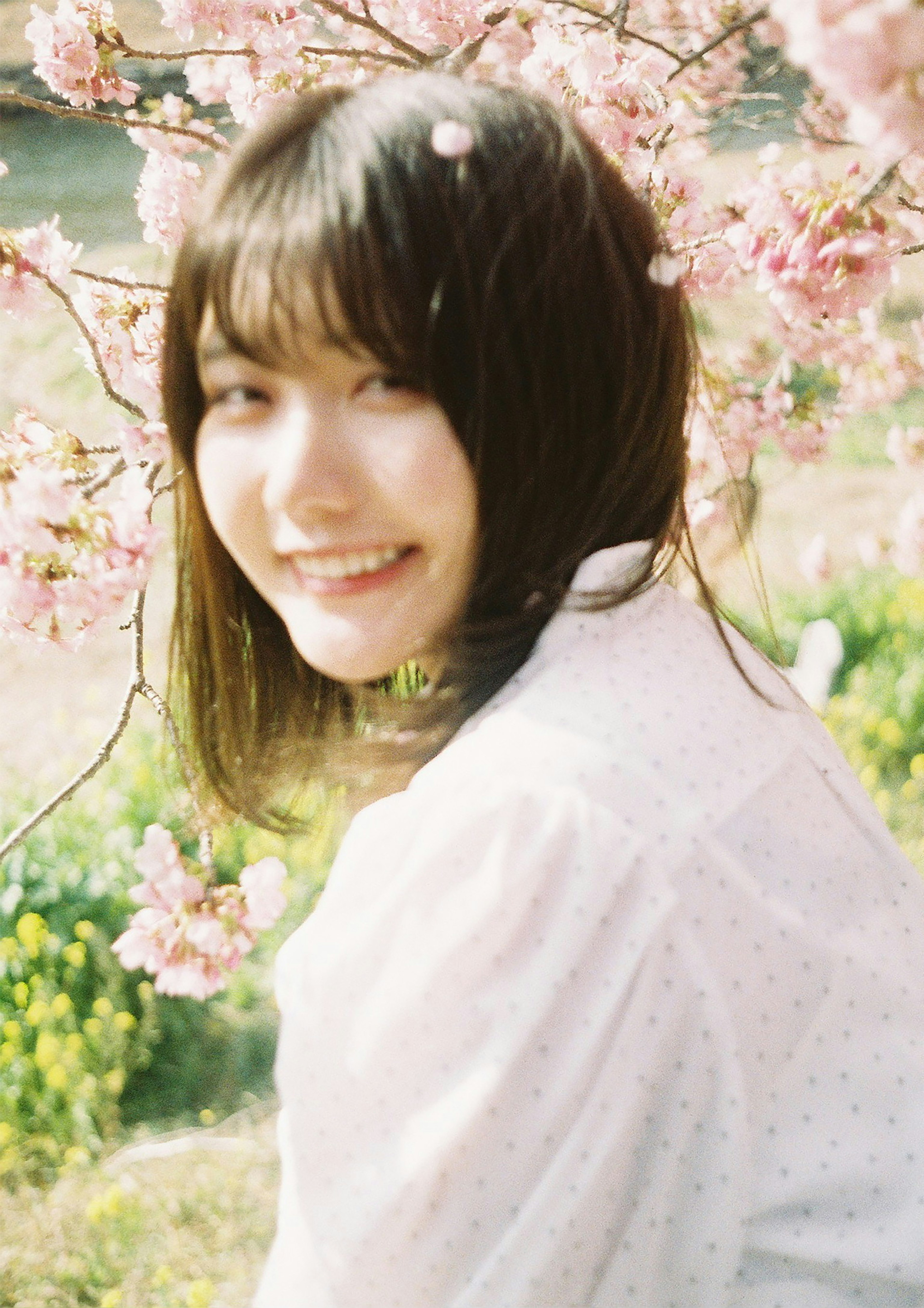 Portrait d'une femme souriante devant des cerisiers en fleurs