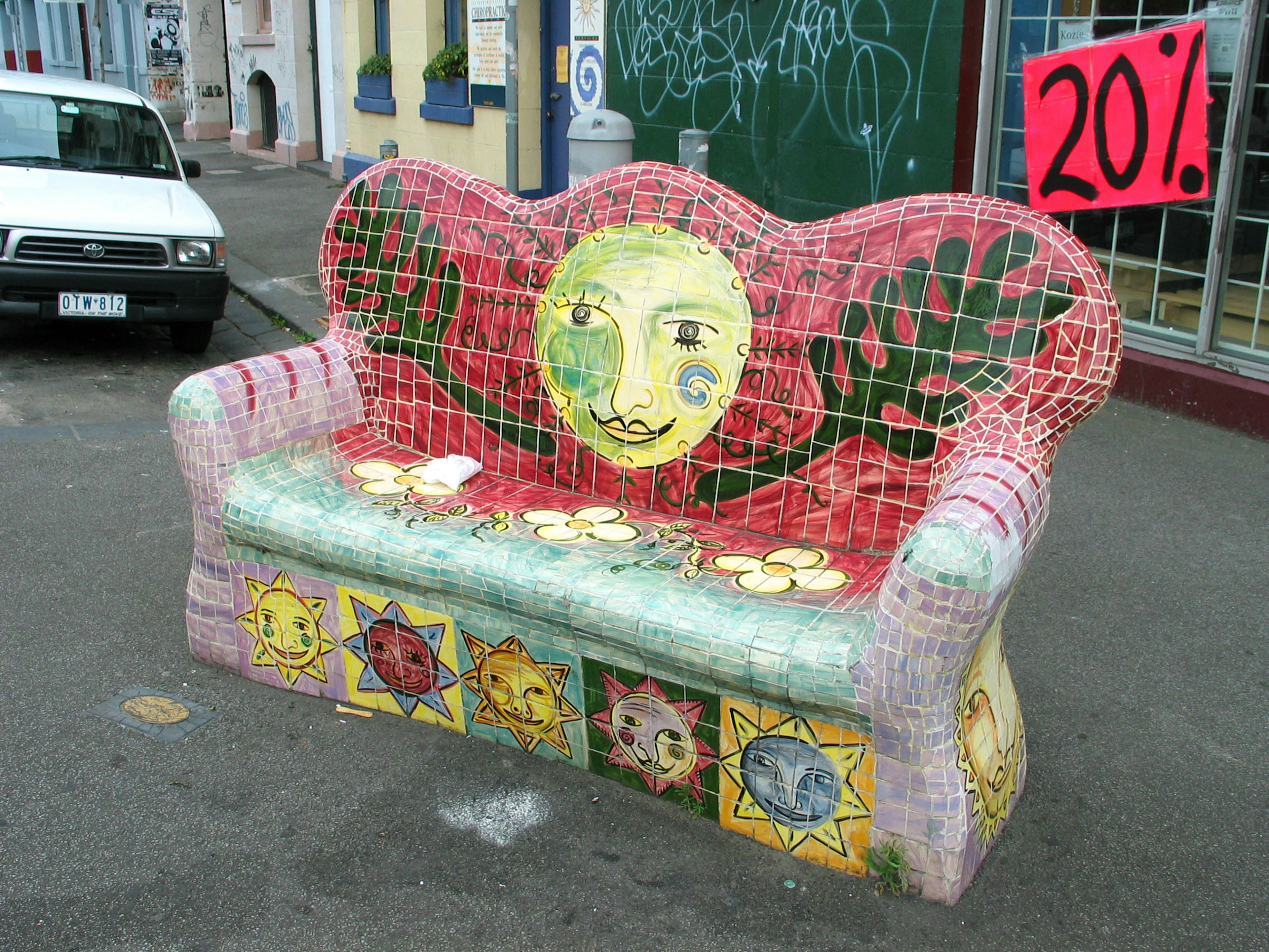 Colorful mosaic bench with sun and flower designs in an urban setting