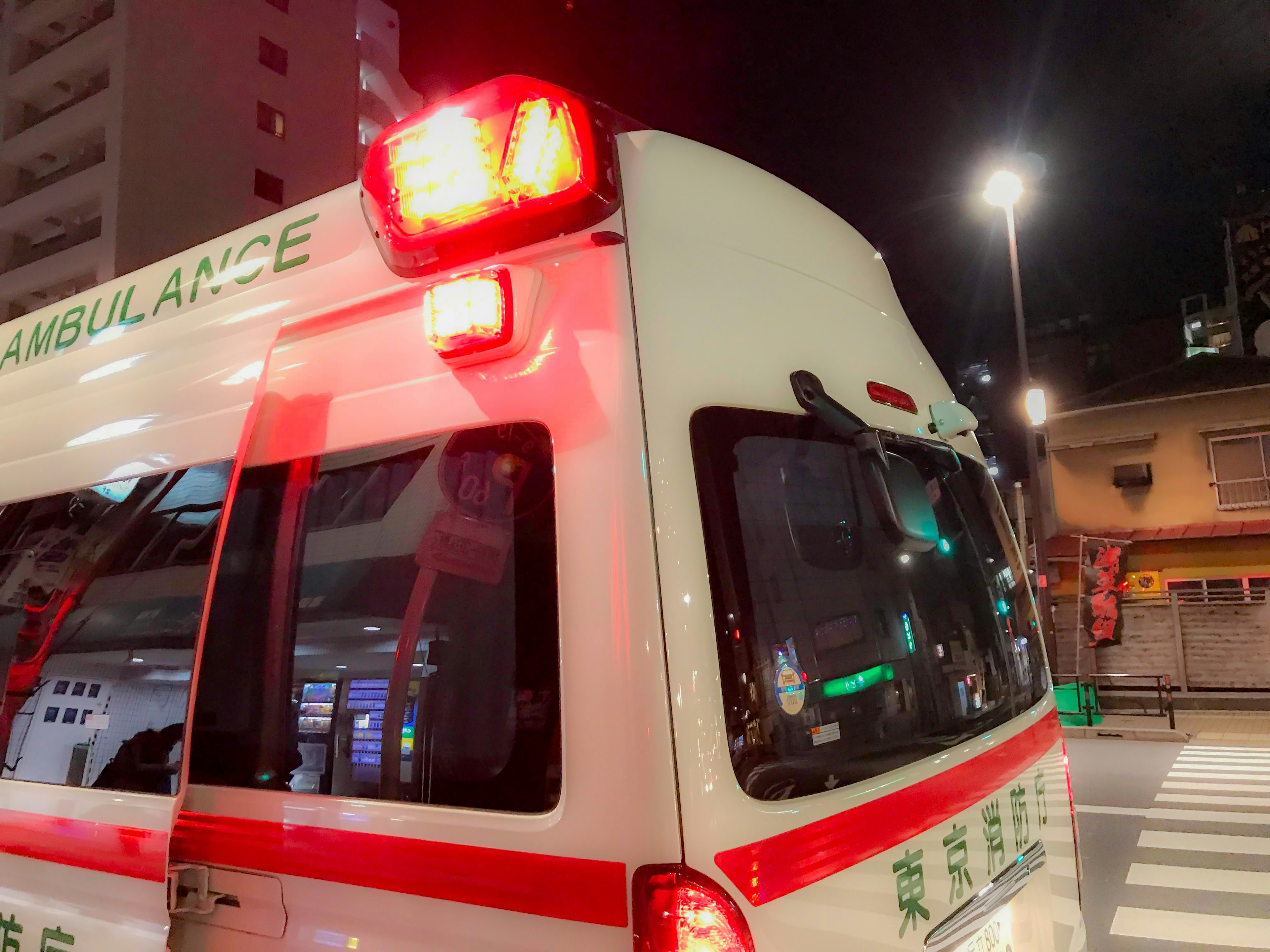 Ambulancia estacionada en la ciudad de noche luz roja intermitente y carrocería blanca