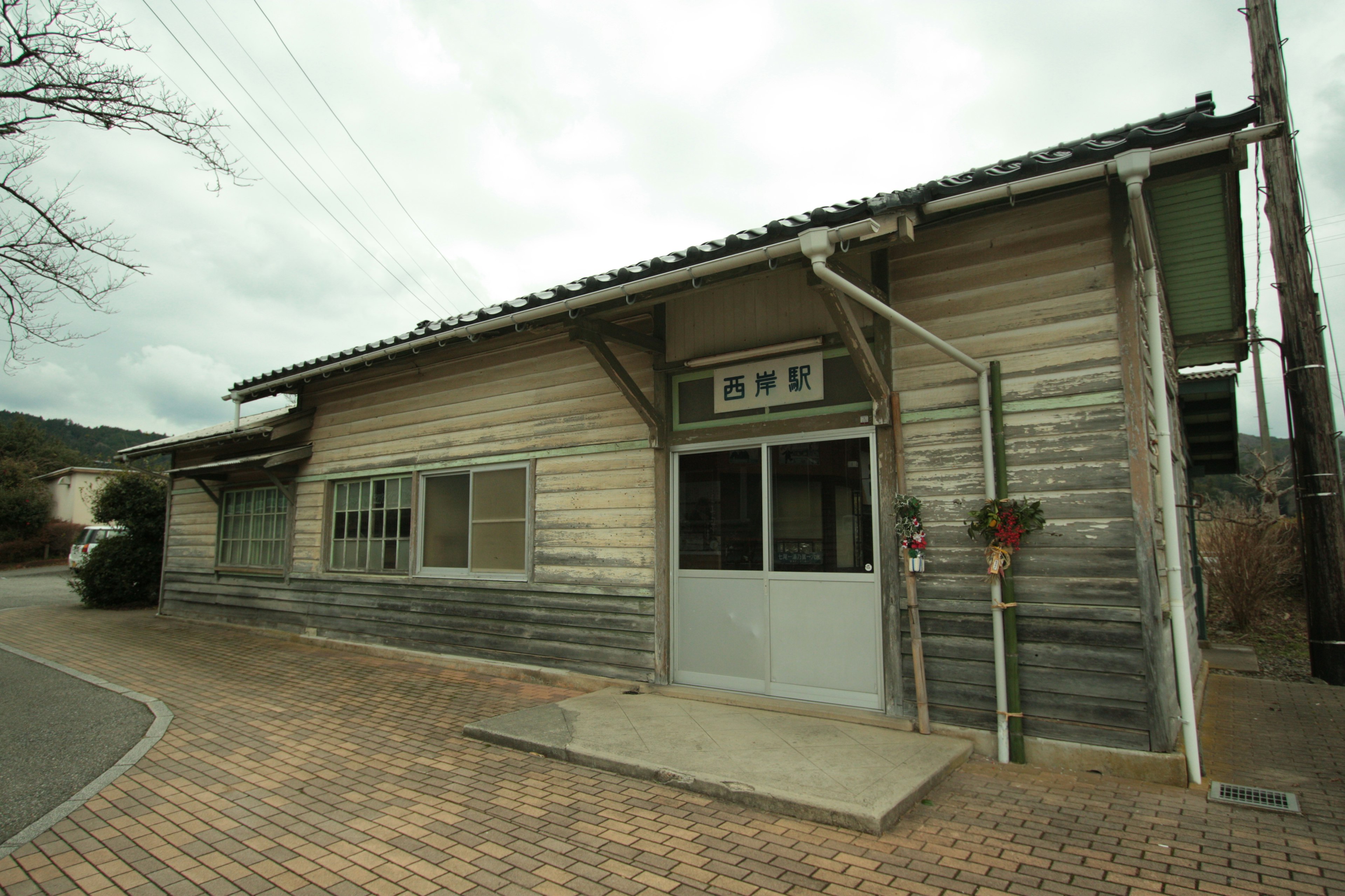 Antiguo edificio de madera con varias ventanas y un camino pavimentado en los alrededores