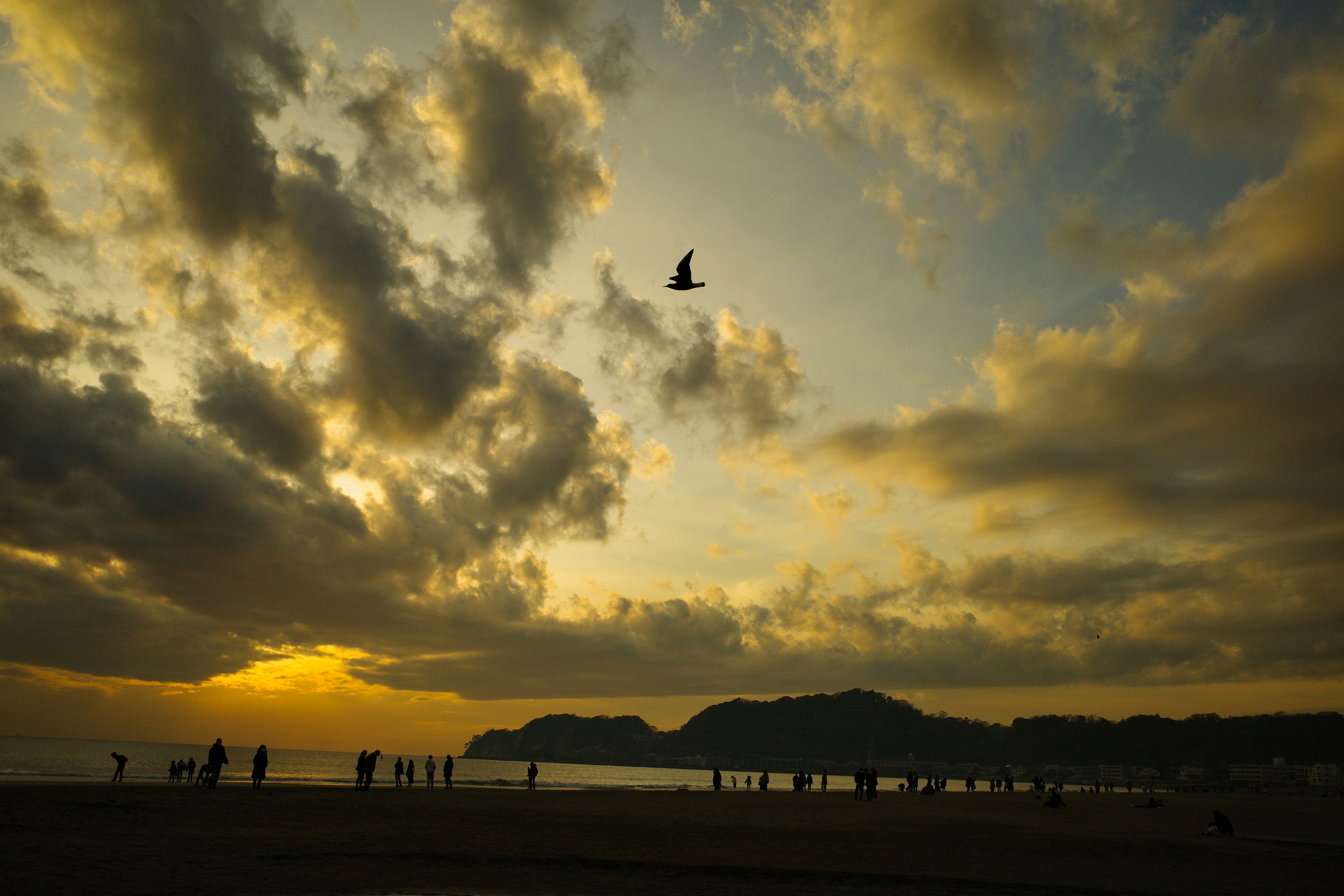 夕日が沈む海岸で人々が歩くシルエットと雲の美しい風景