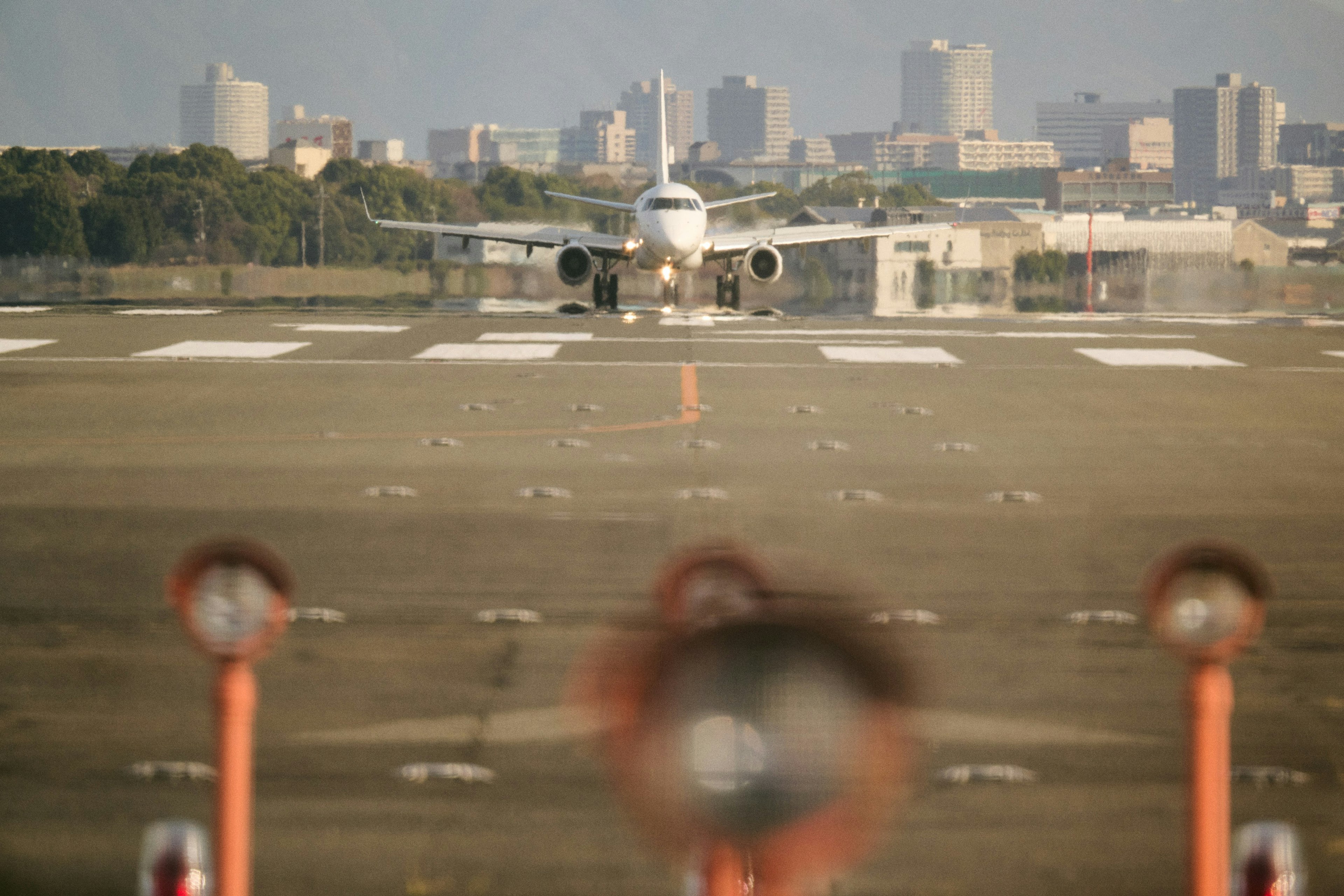 Airplane taxiing on runway with city skyline in background