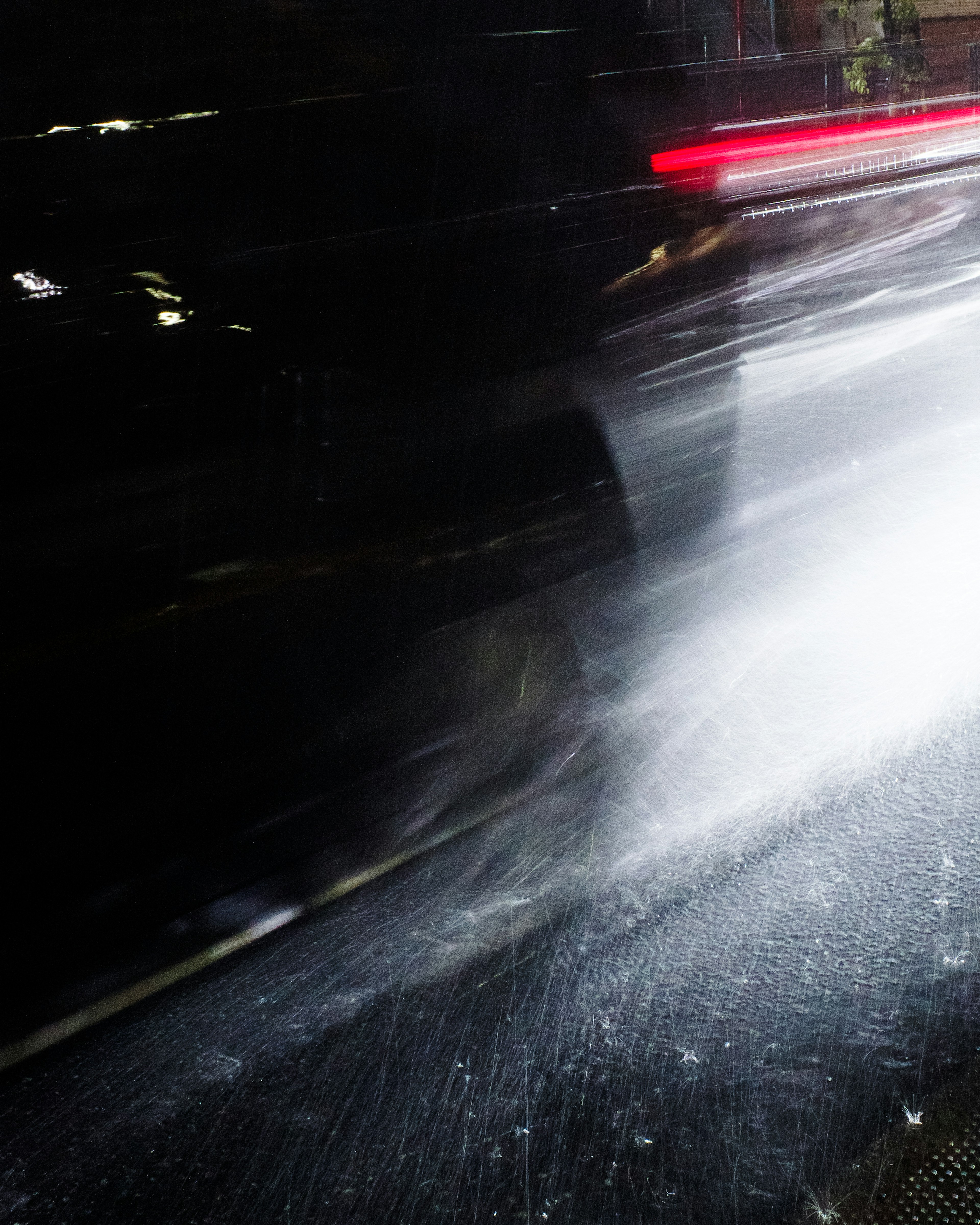 Wasserspritzer von einem Auto, das nachts fährt, mit roten Rücklichtern