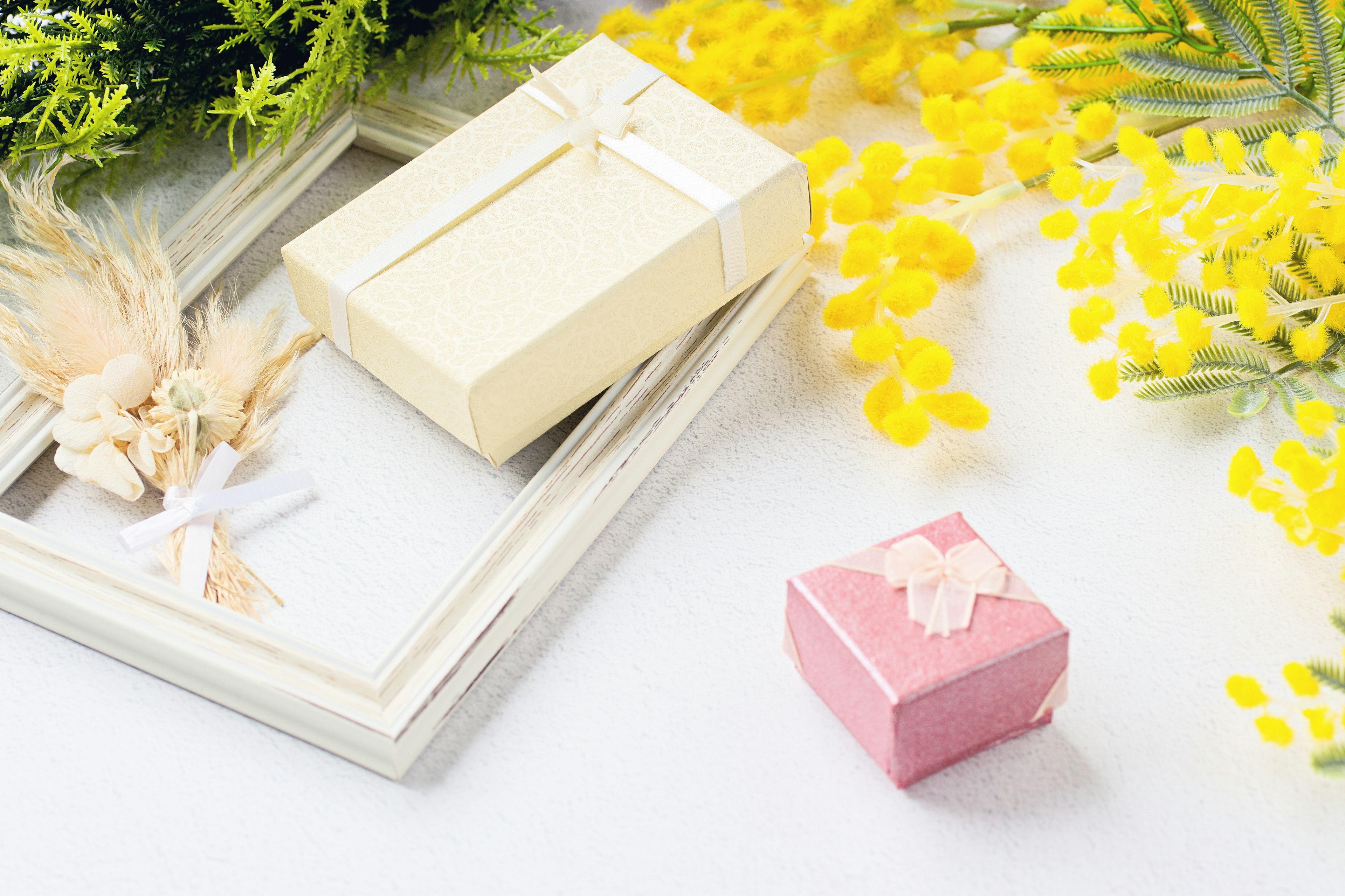 Small white and pink gift boxes beside a frame with yellow flowers