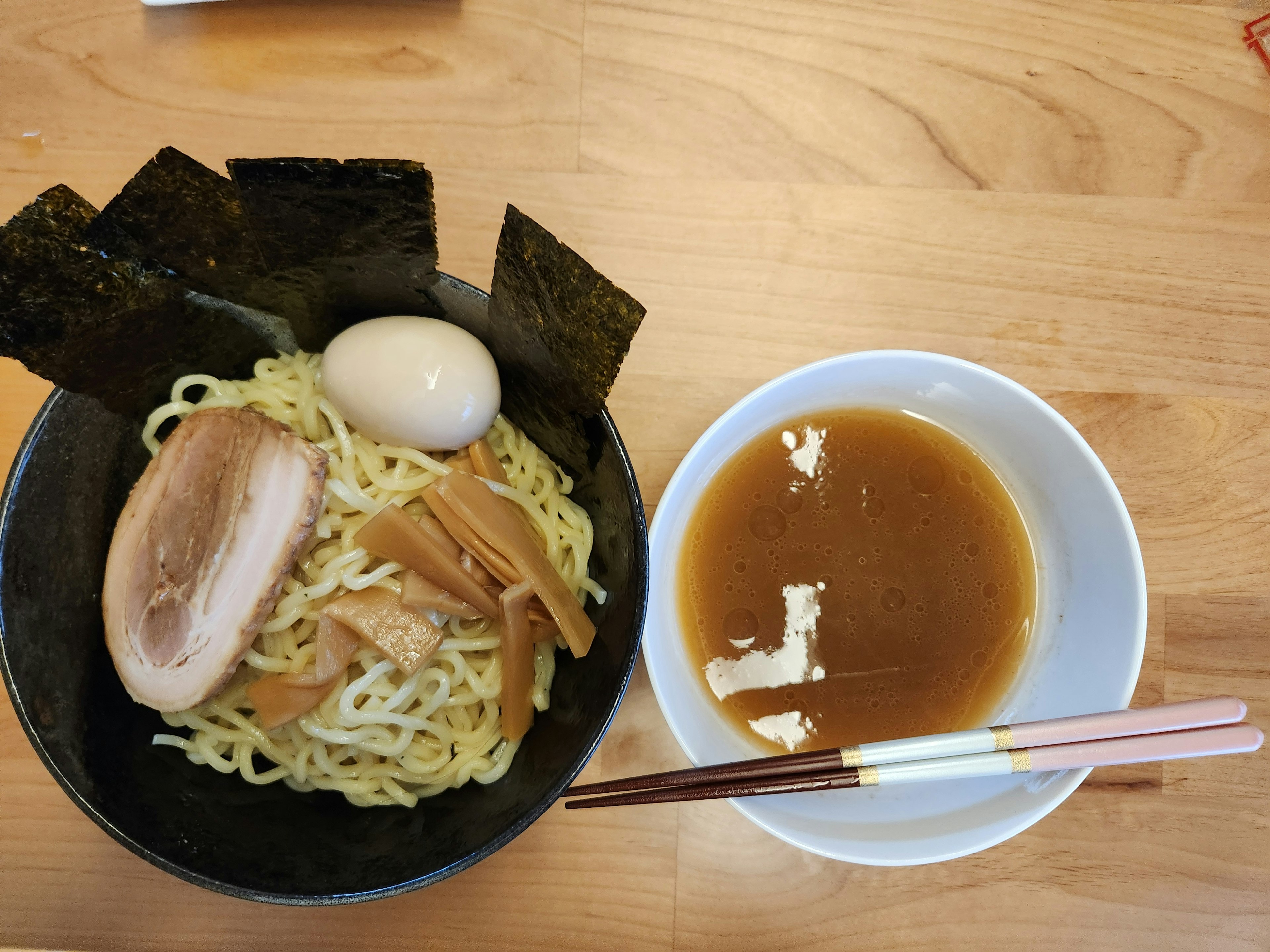 ラーメンとスープの皿の写真　チャーシューと煮卵と海苔が添えられている