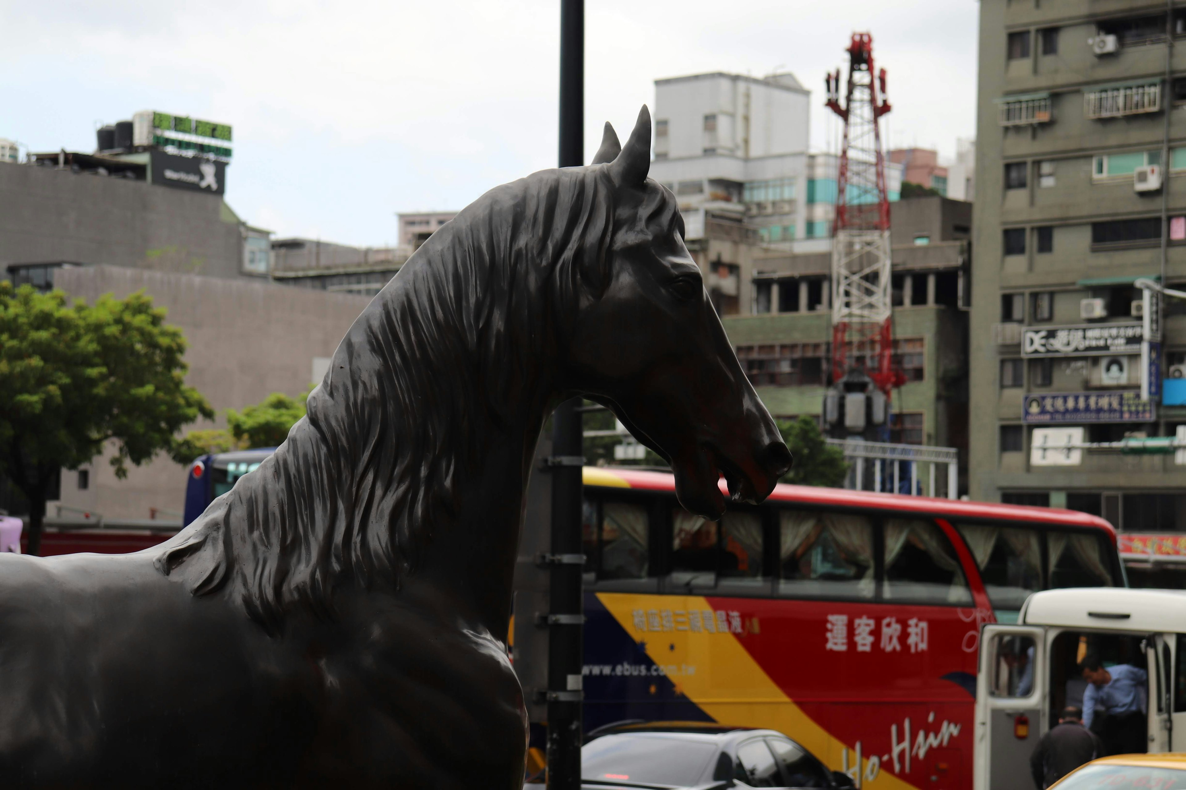 Una scultura di cavallo in città con autobus sullo sfondo