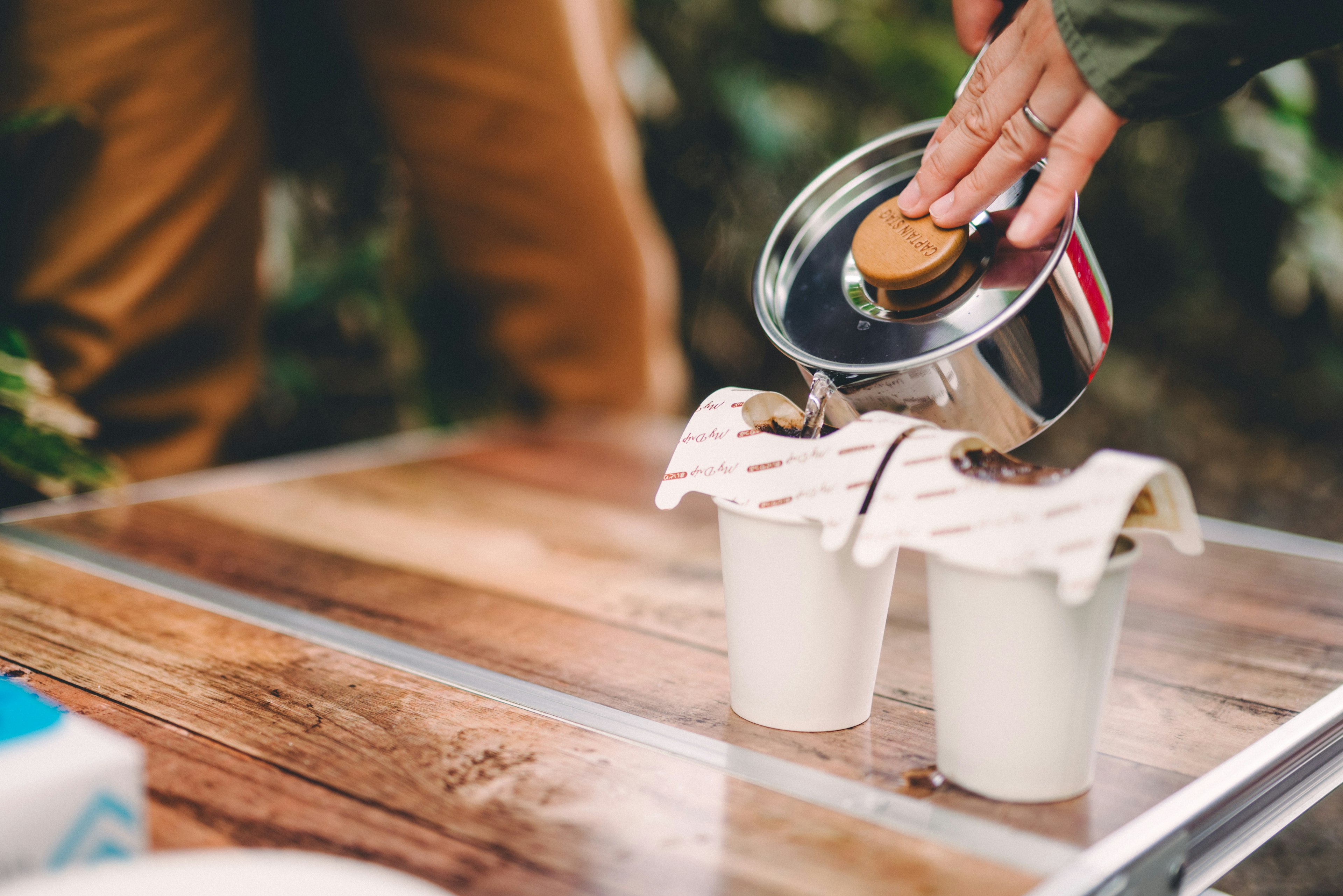 Nahaufnahme einer Hand, die einen Deckel auf Kaffeetassen setzt