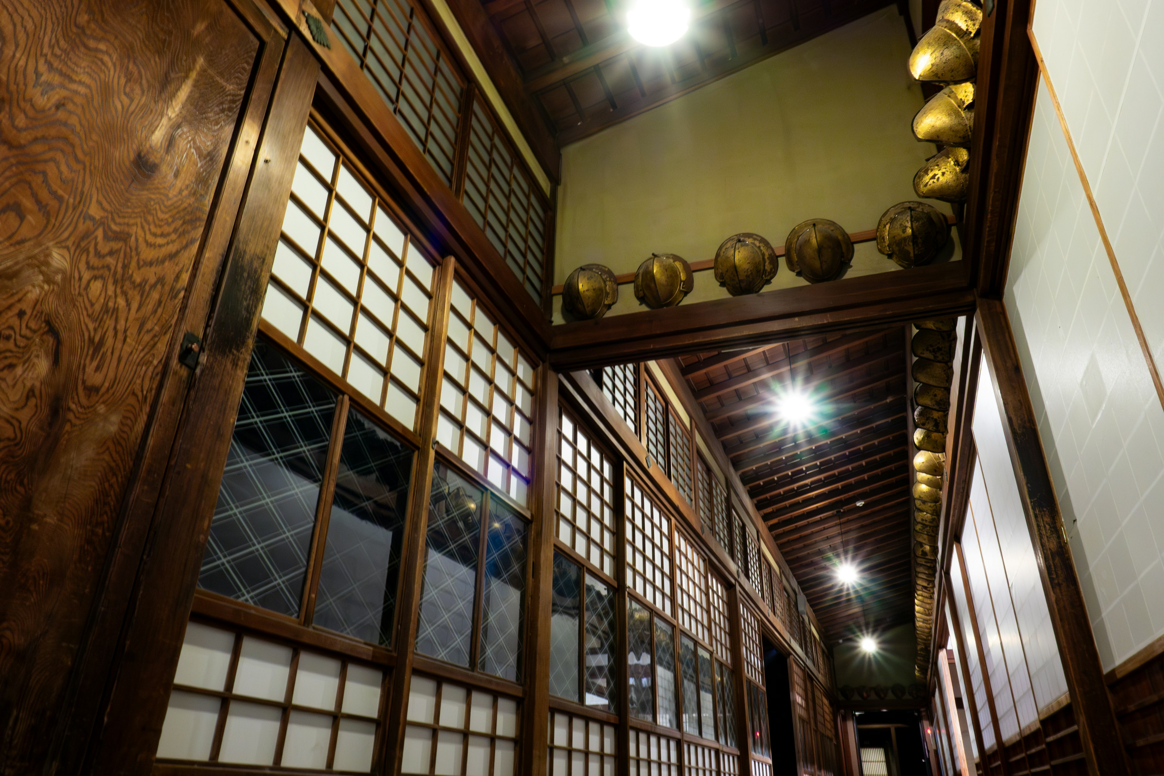 Traditional Japanese house hallway with wooden walls and shoji screens featuring golden decorations on the ceiling