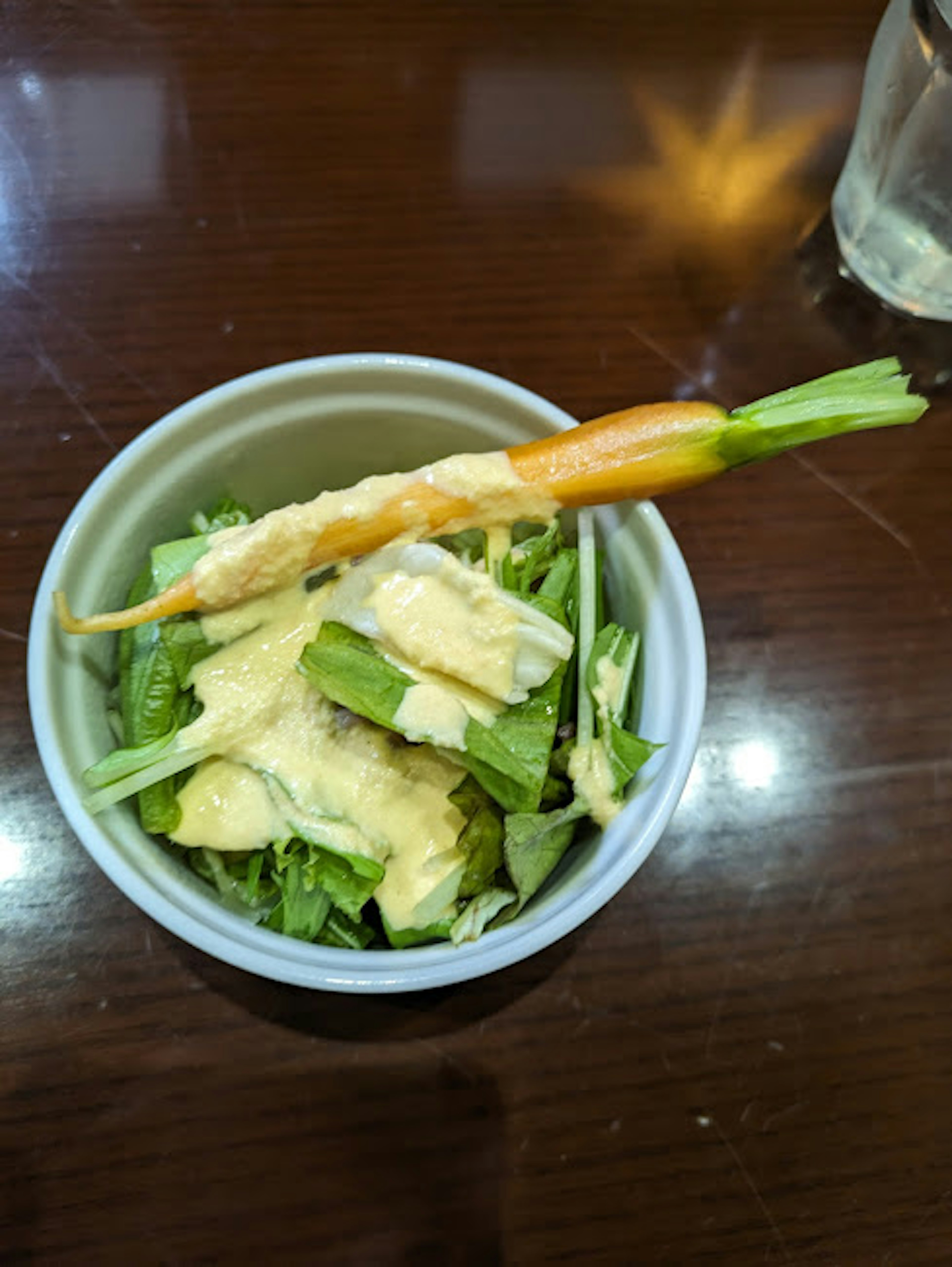 Pequeño tazón con ensalada de verduras frescas decorado con zanahoria