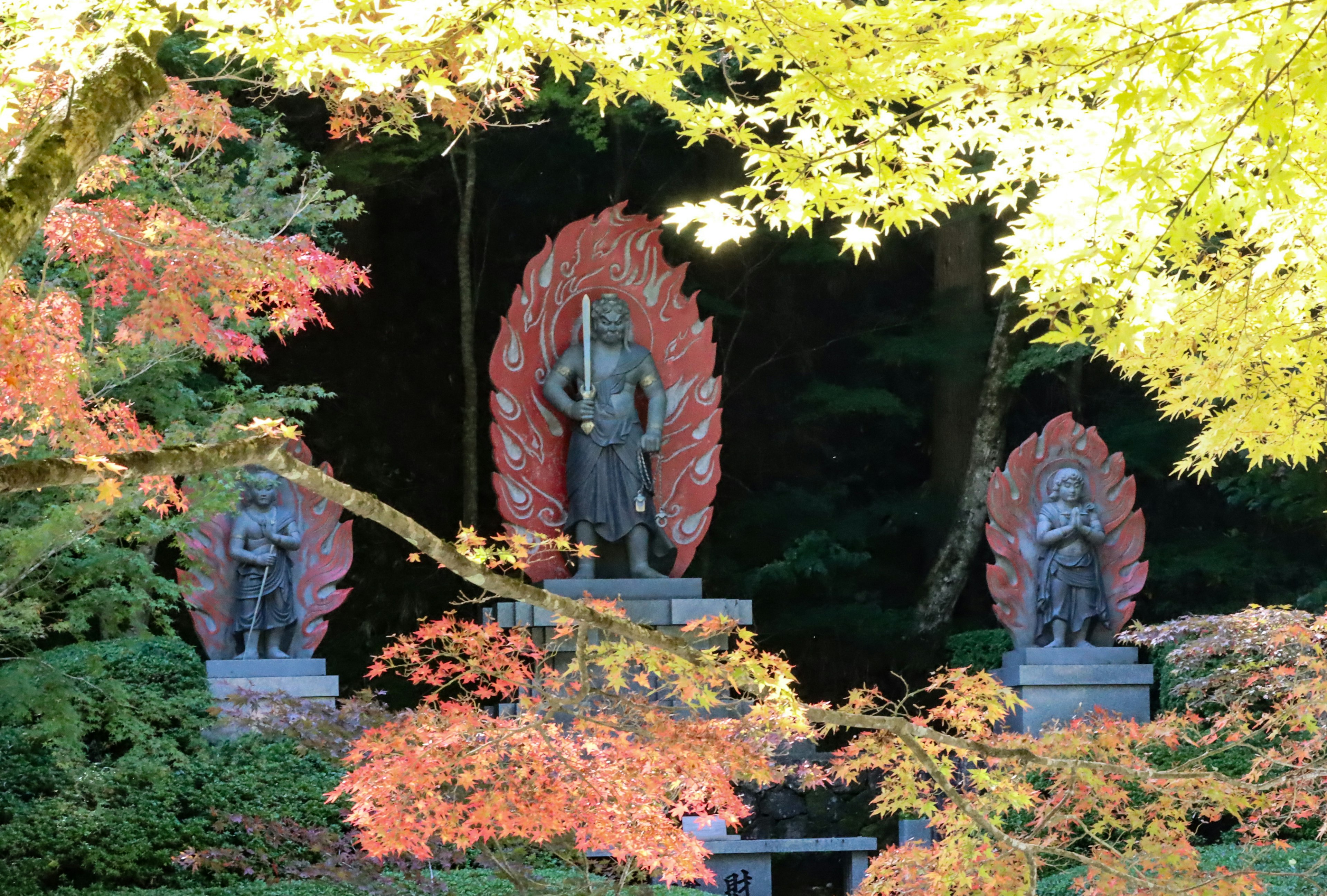 美しい秋の紅葉に囲まれた三体の仏像