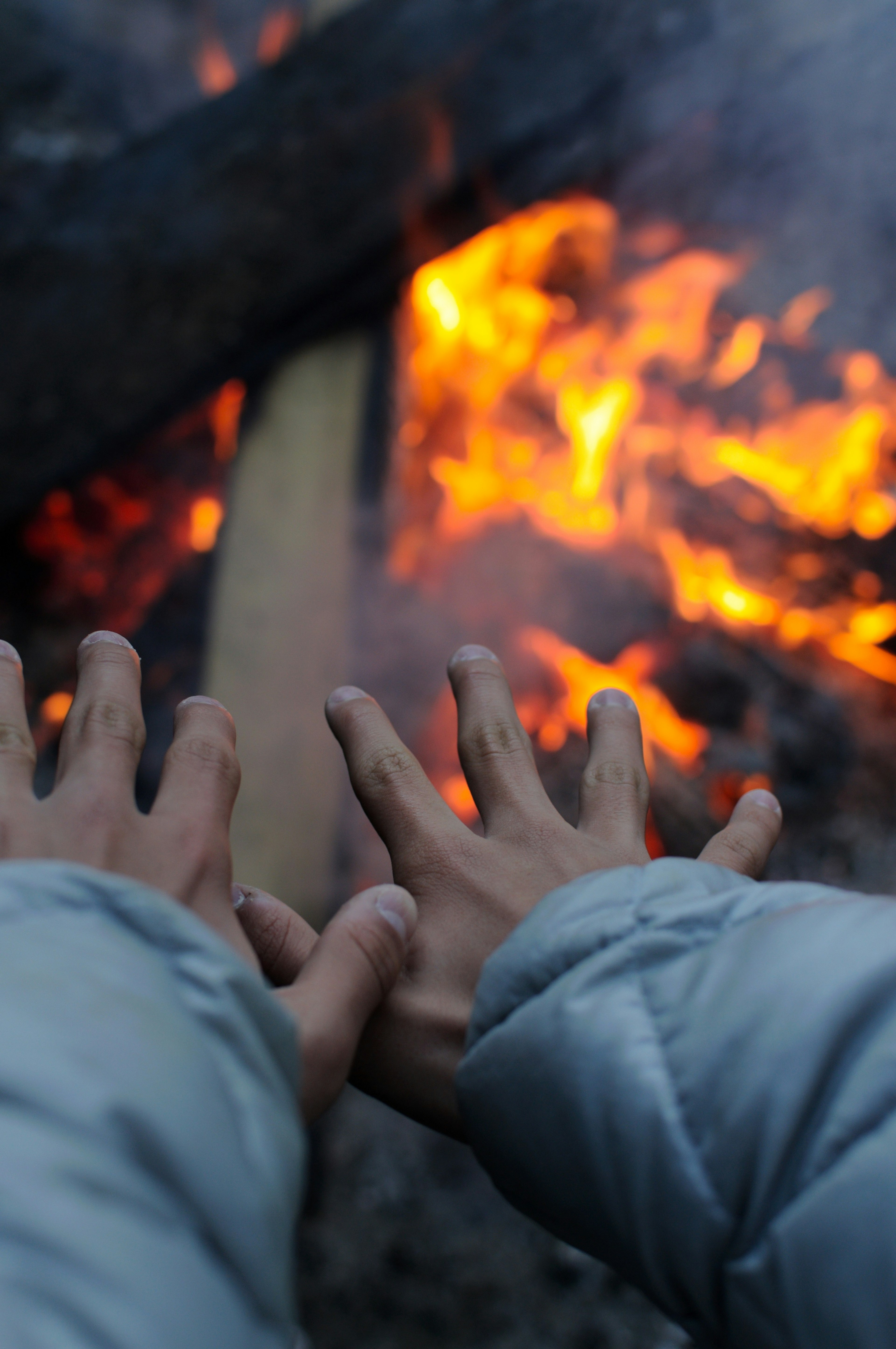 Two hands reaching towards a vibrant fire