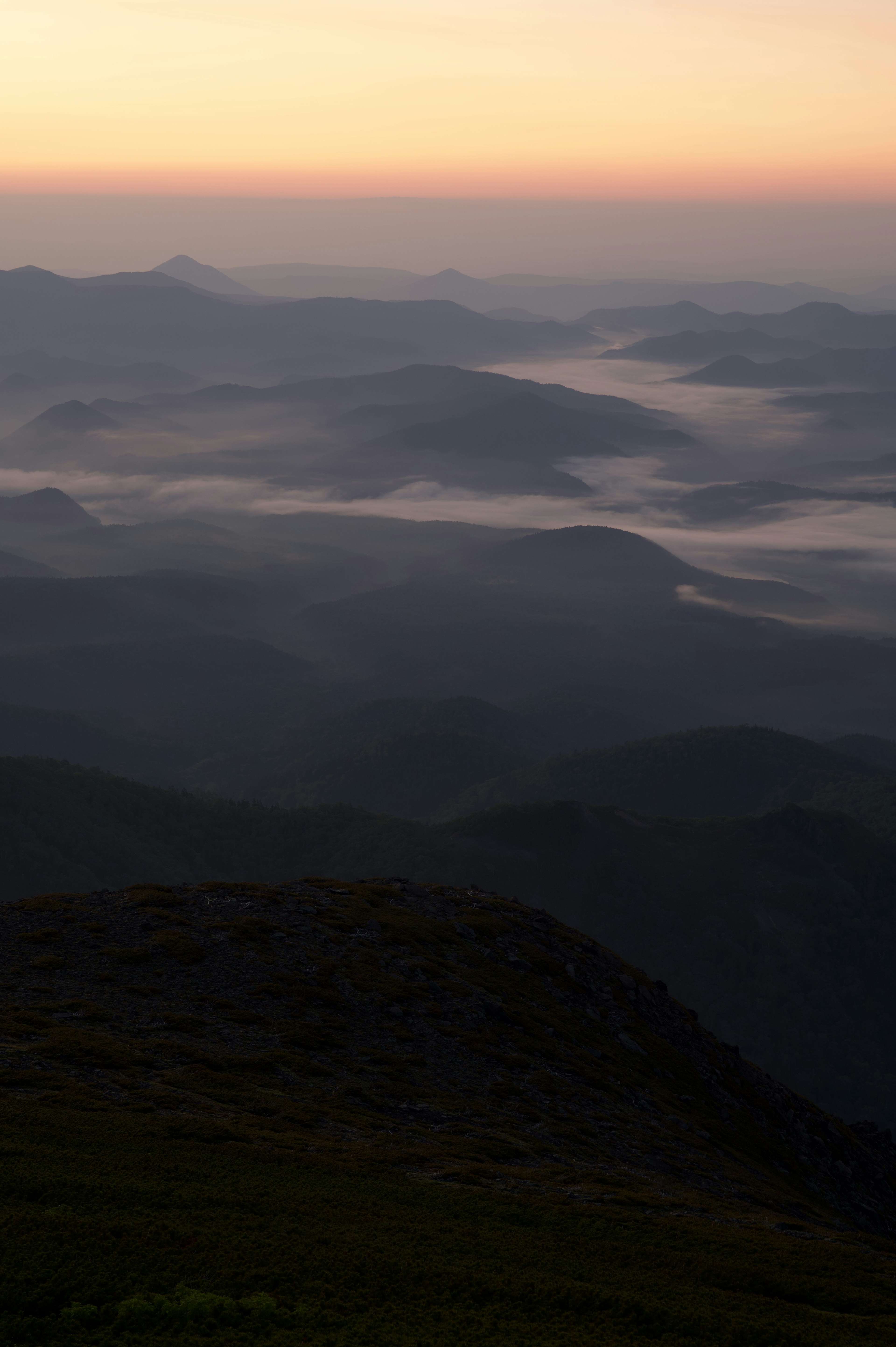 Silhouetten von Bergen bei Sonnenuntergang mit nebligen Tälern