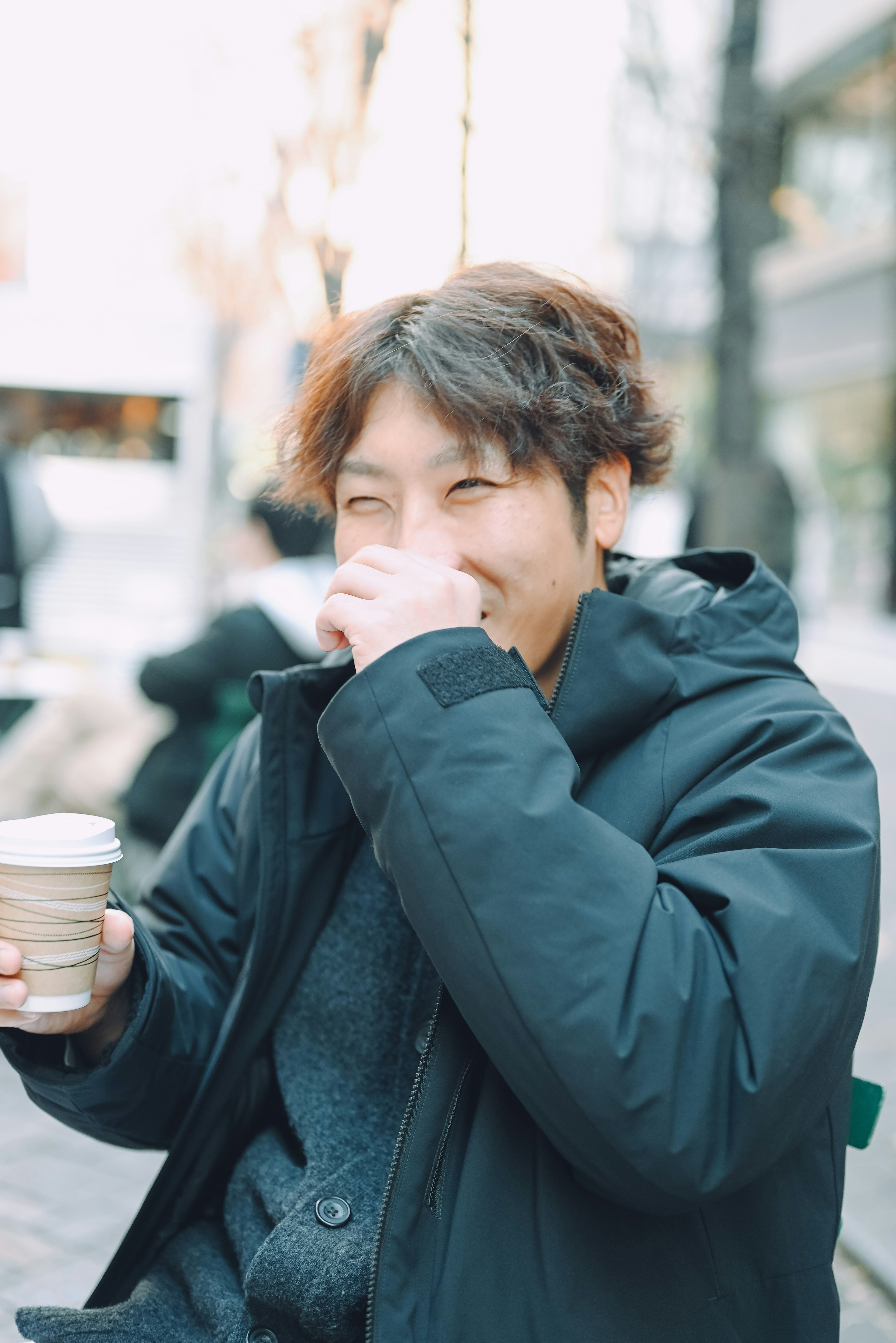 Man smiling while holding a coffee cup in a cafe