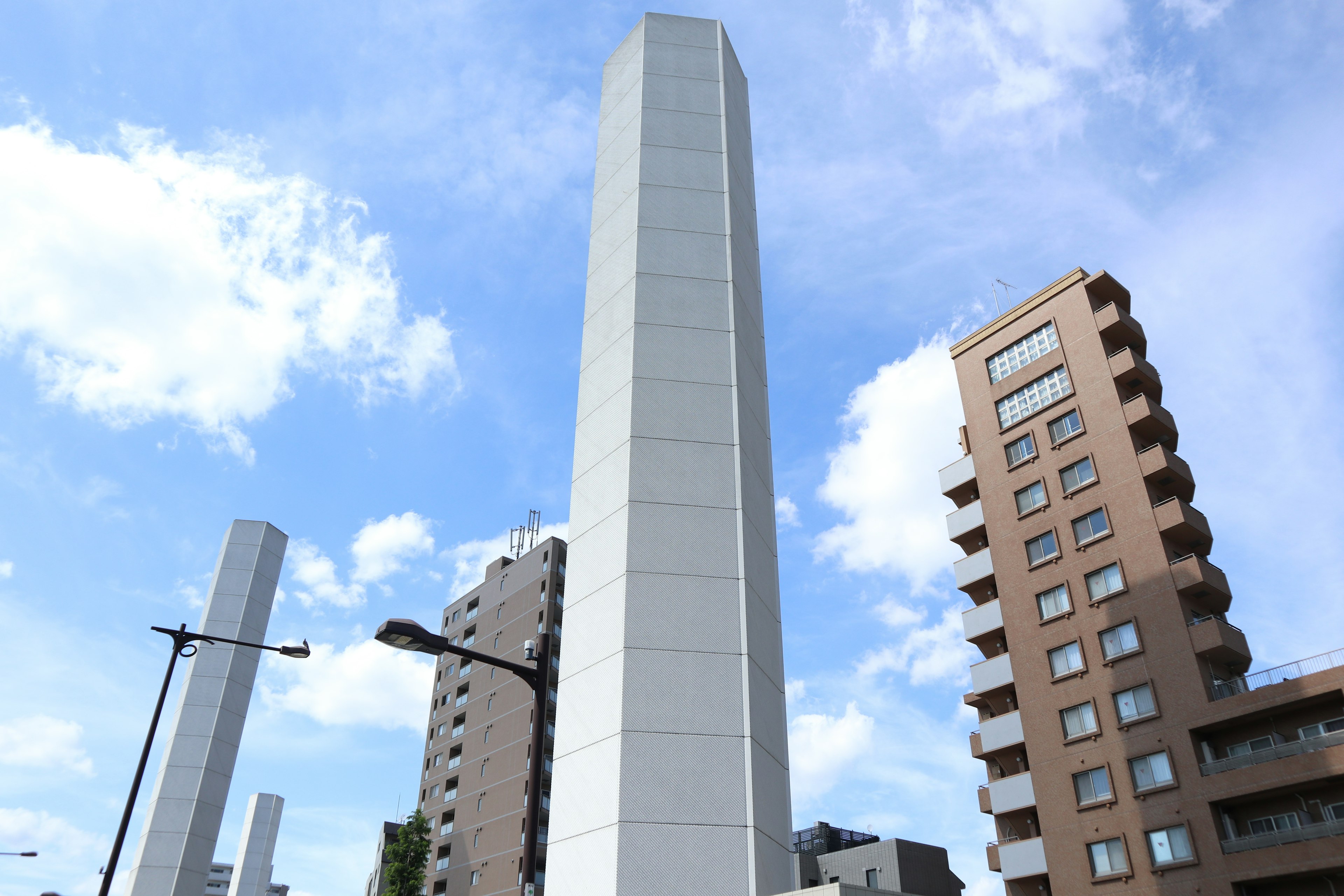 Menara putih tinggi di samping bangunan modern di bawah langit biru