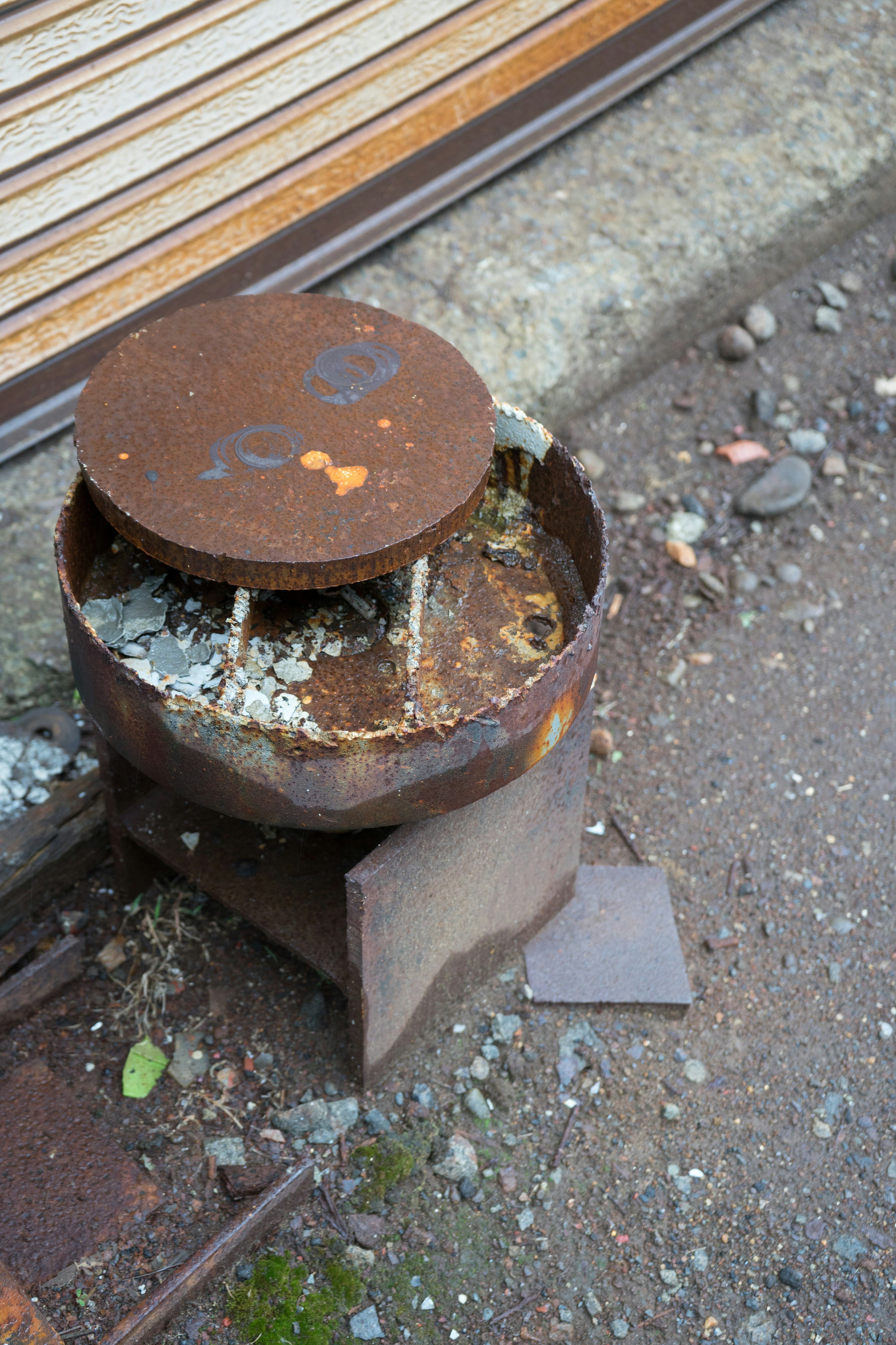 Estufa de metal oxidado colocada en el suelo rodeada de pequeñas piedras