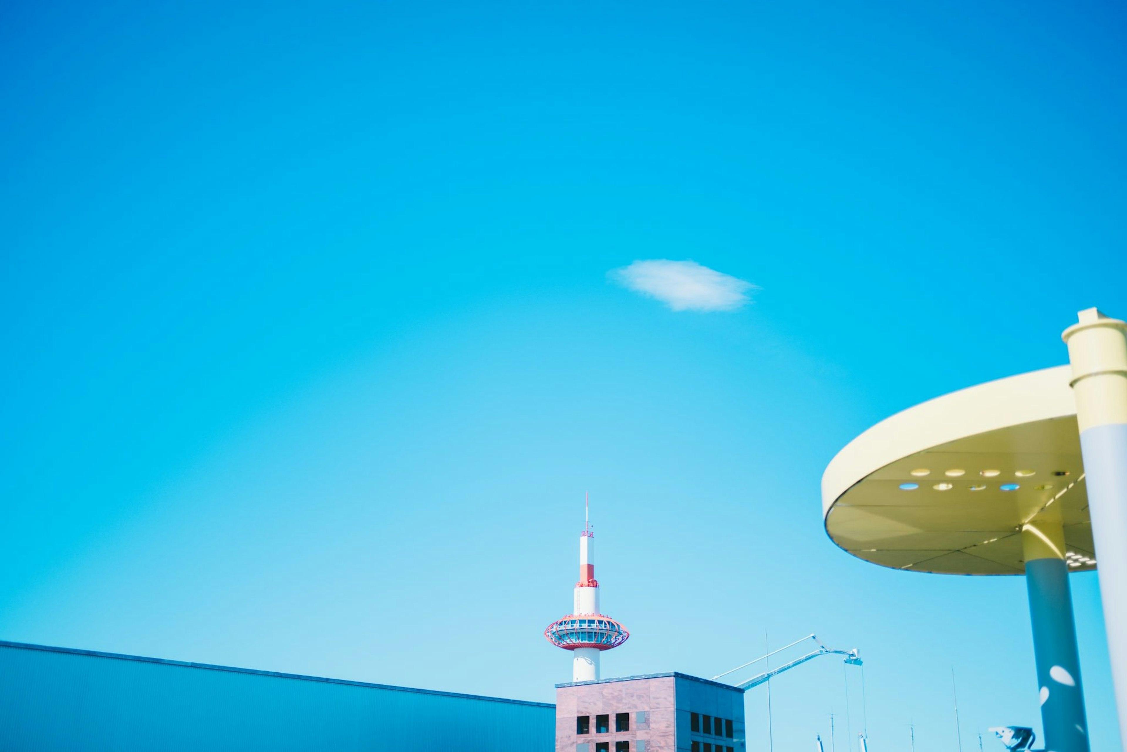 Un edificio moderno con un toldo amarillo bajo un cielo azul brillante y una sola nube