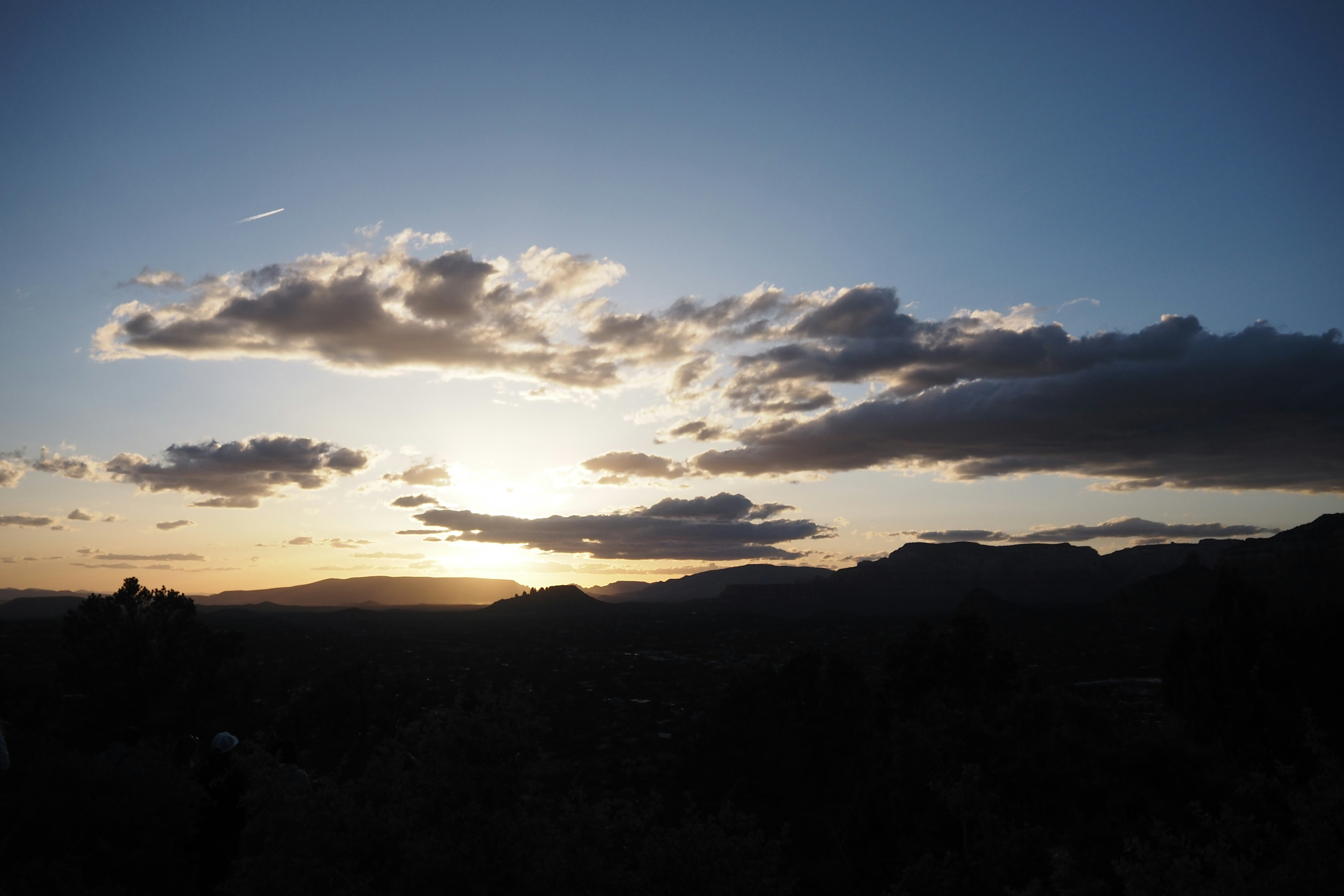 Vista escénica de un atardecer con nubes y montañas en silueta