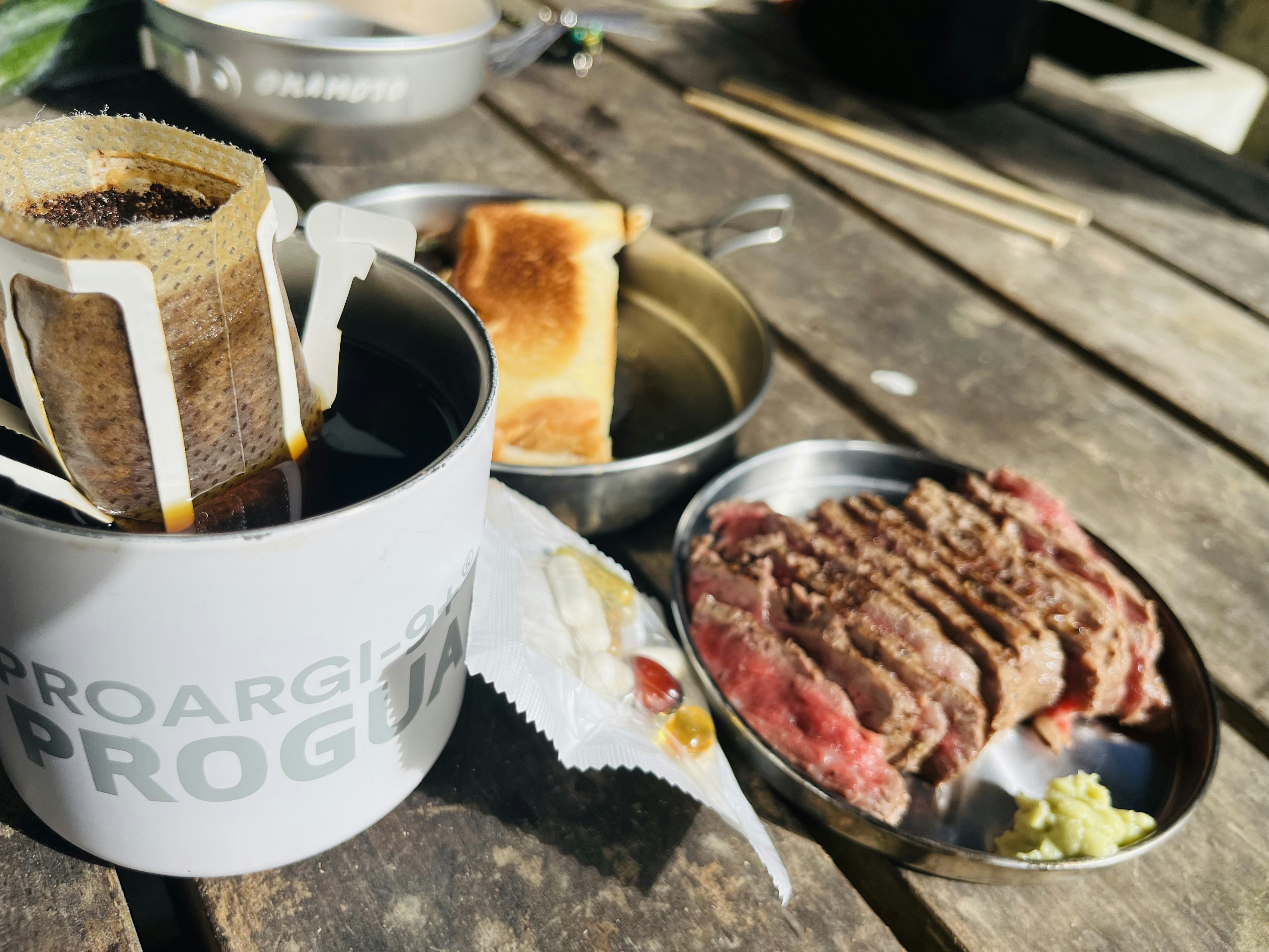 テーブルの上に置かれたコーヒー、トースト、焼肉の皿