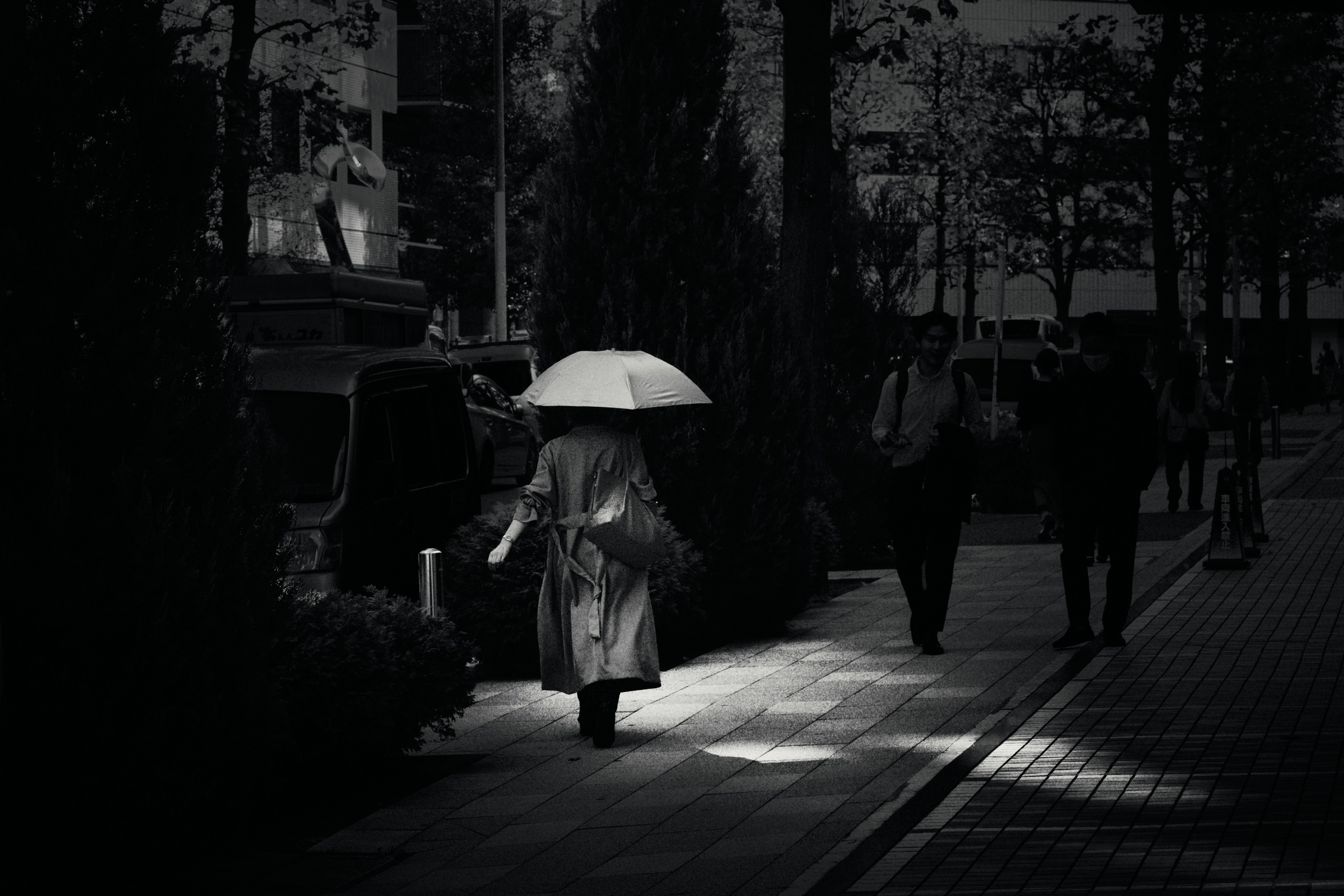 Une personne marchant dans la ville avec un parapluie dans un cadre noir et blanc