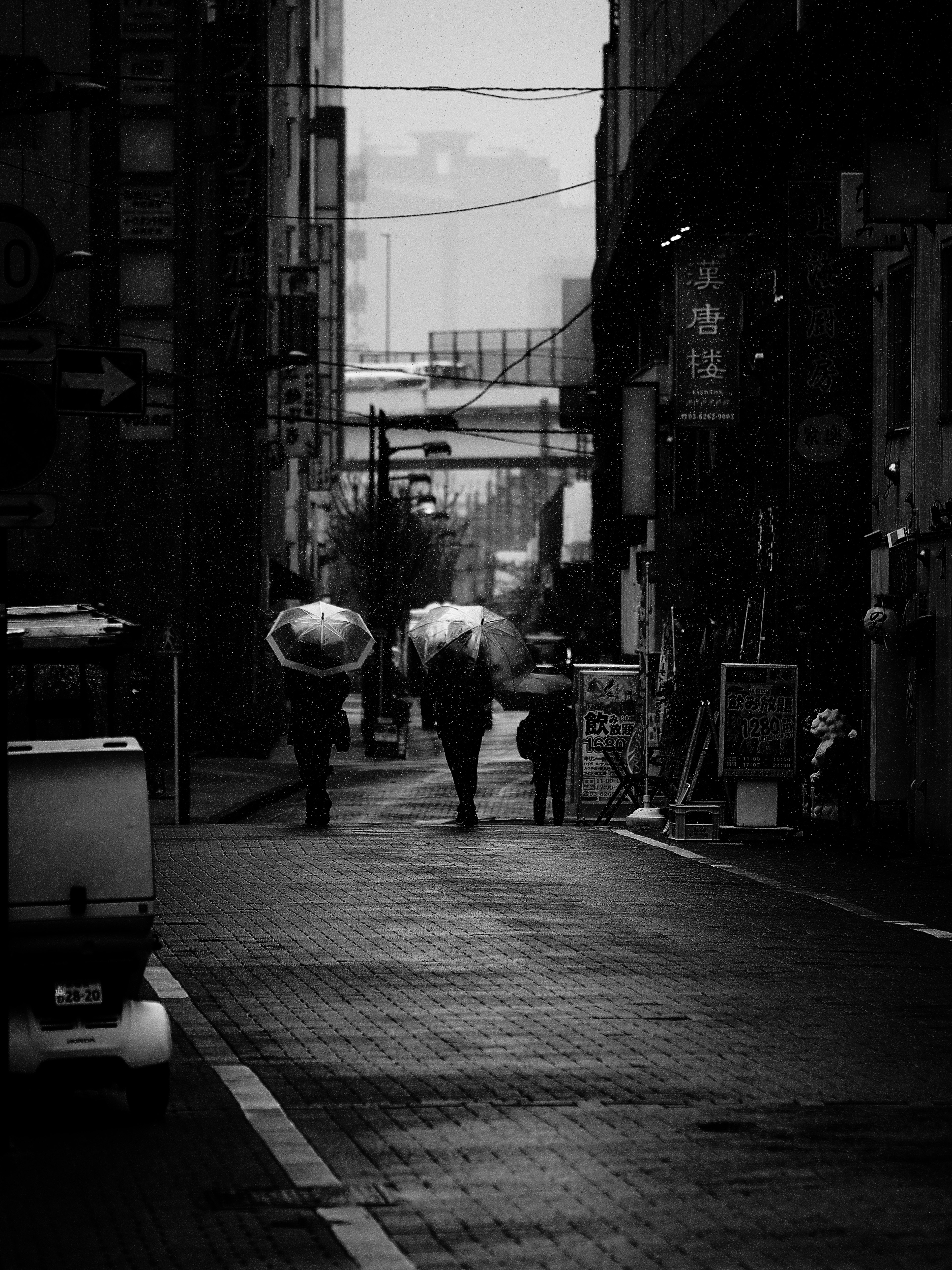 Foto en blanco y negro de personas caminando con paraguas bajo la lluvia