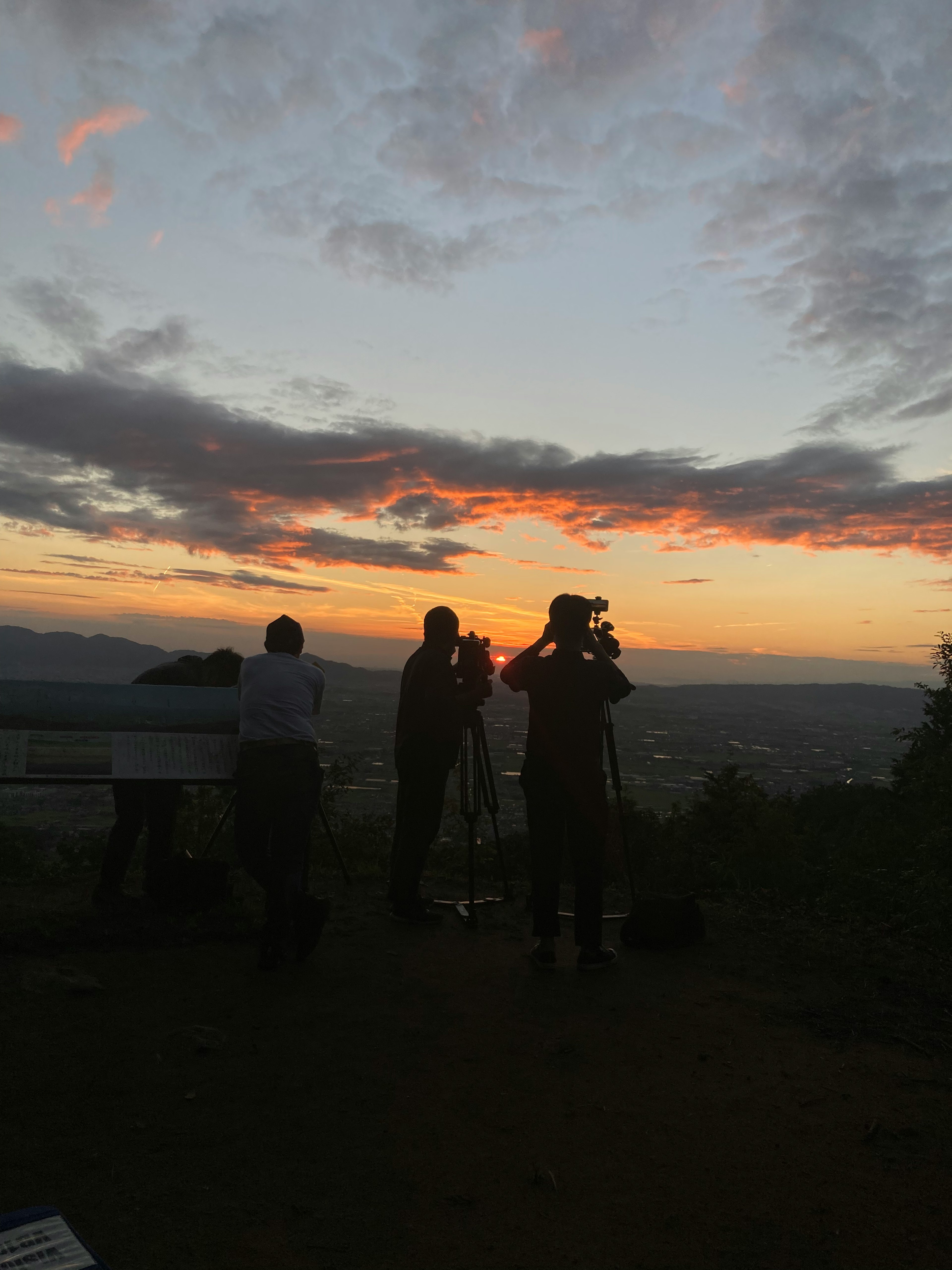 Silhouetten von Menschen, die Teleskope gegen einen Sonnenuntergang benutzen