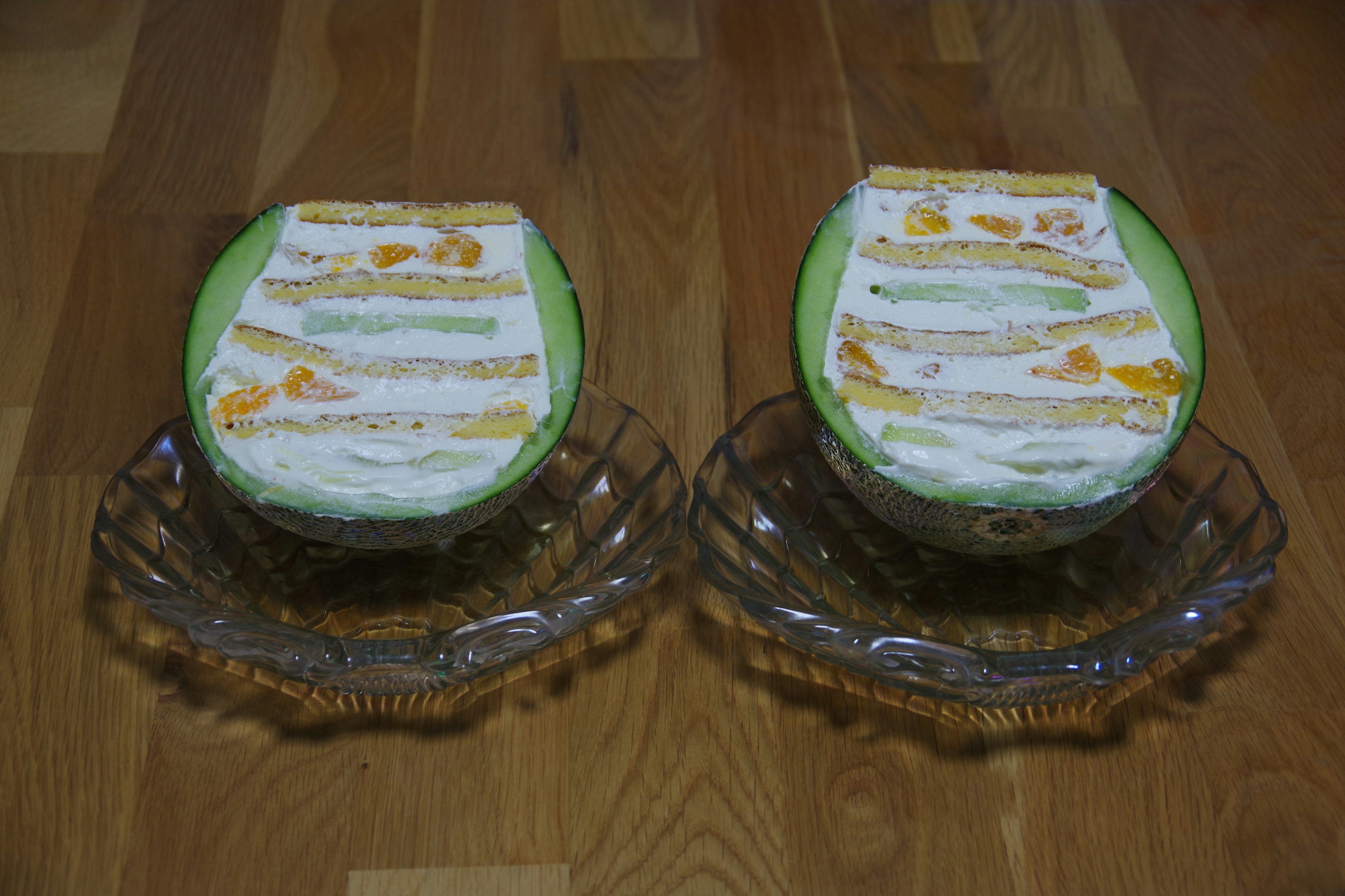 Two halved melons displayed on decorative glass plates