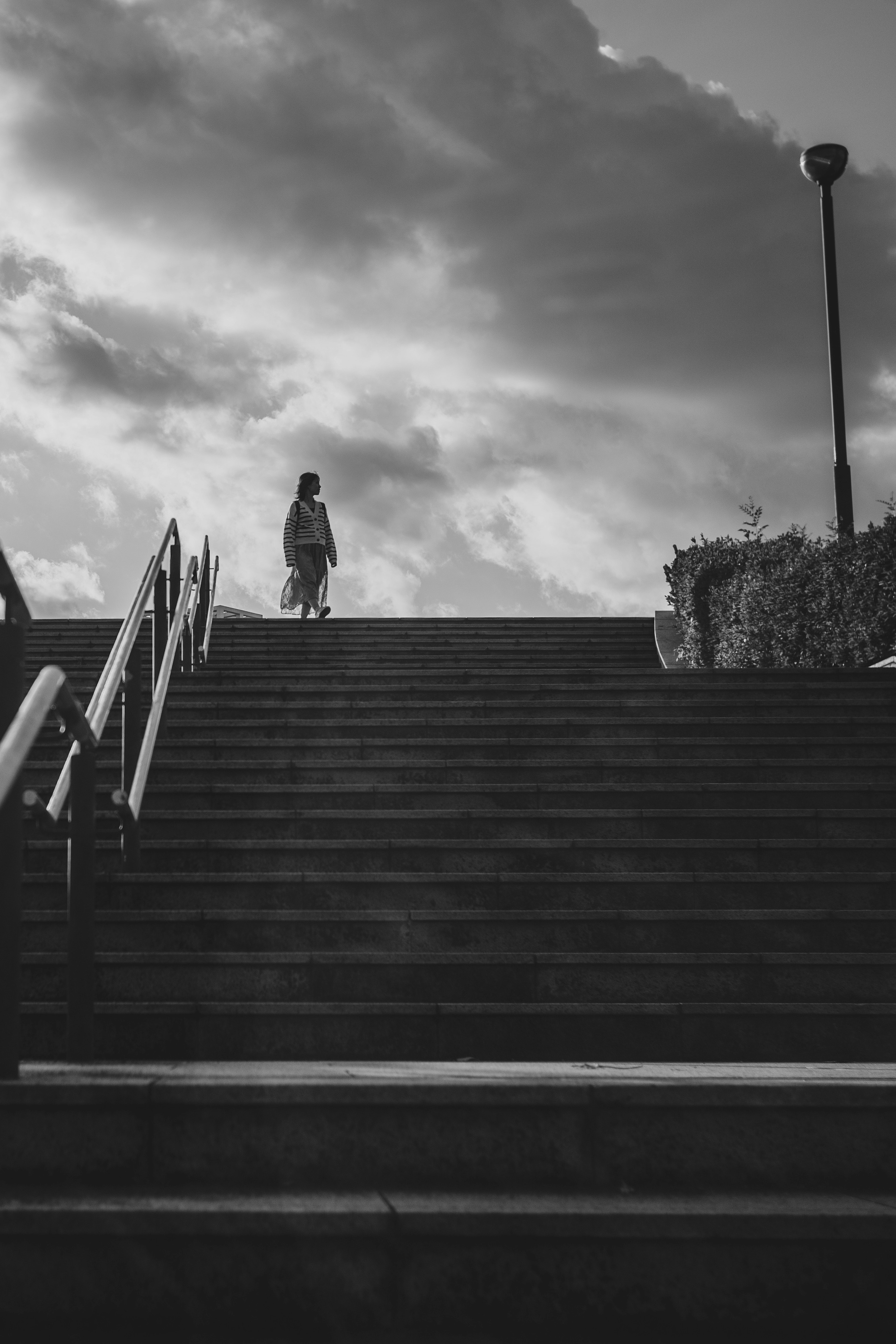 Silhouette d'une personne montant des escaliers sous un ciel nuageux