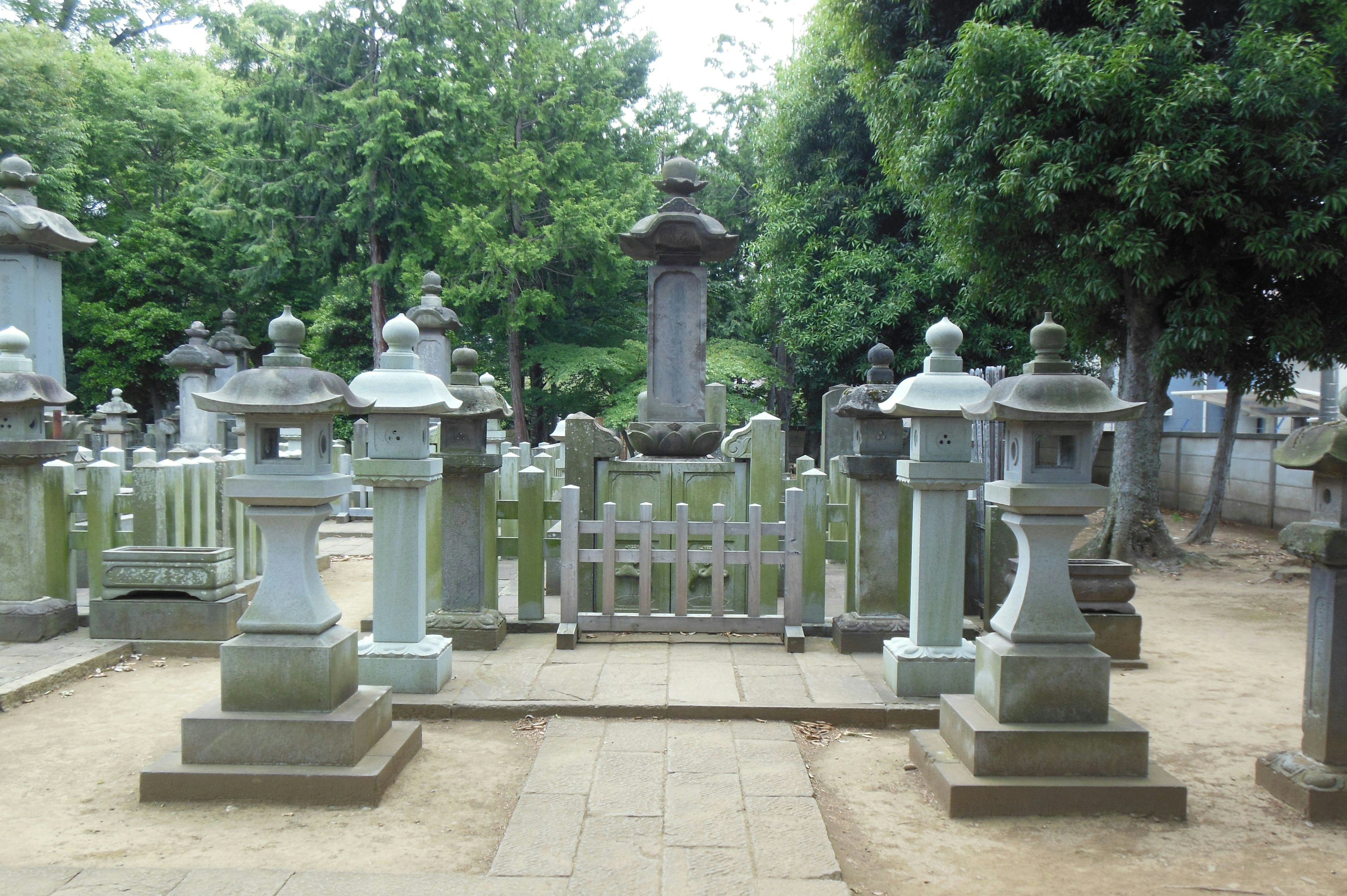 A serene cemetery scene featuring stone lanterns surrounded by greenery