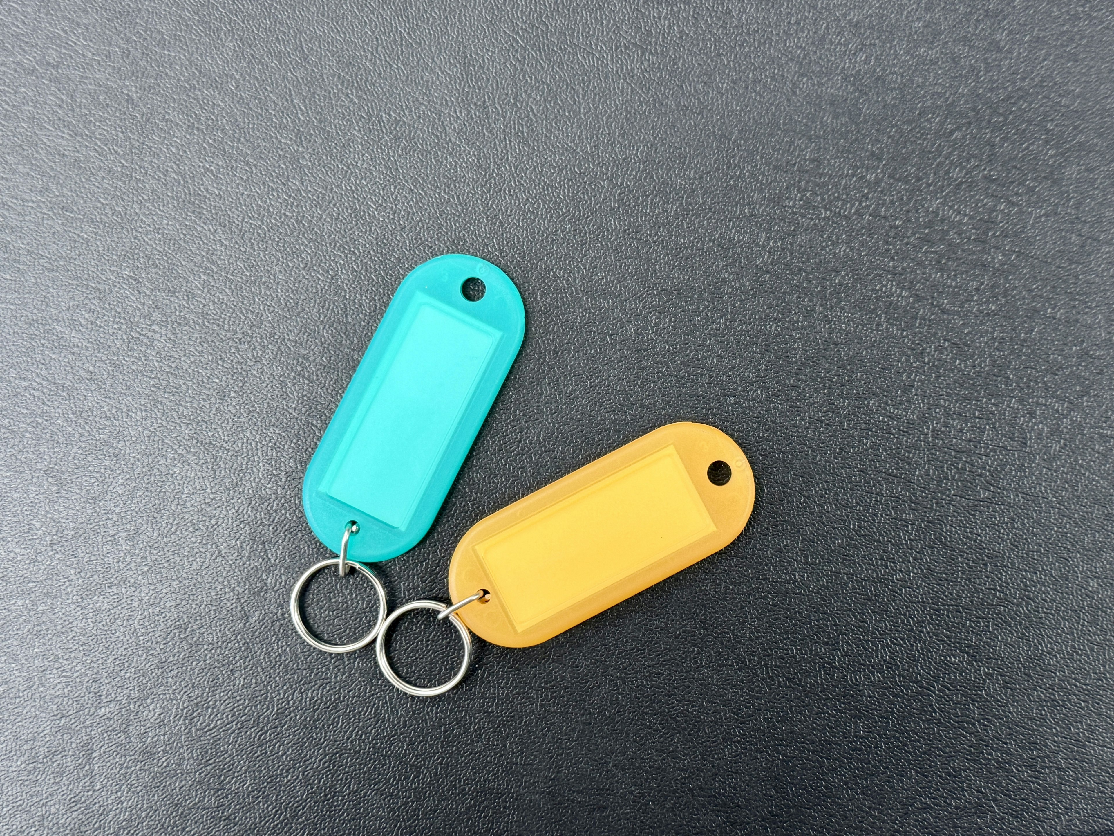 Two plastic keychains in blue and yellow on a black background