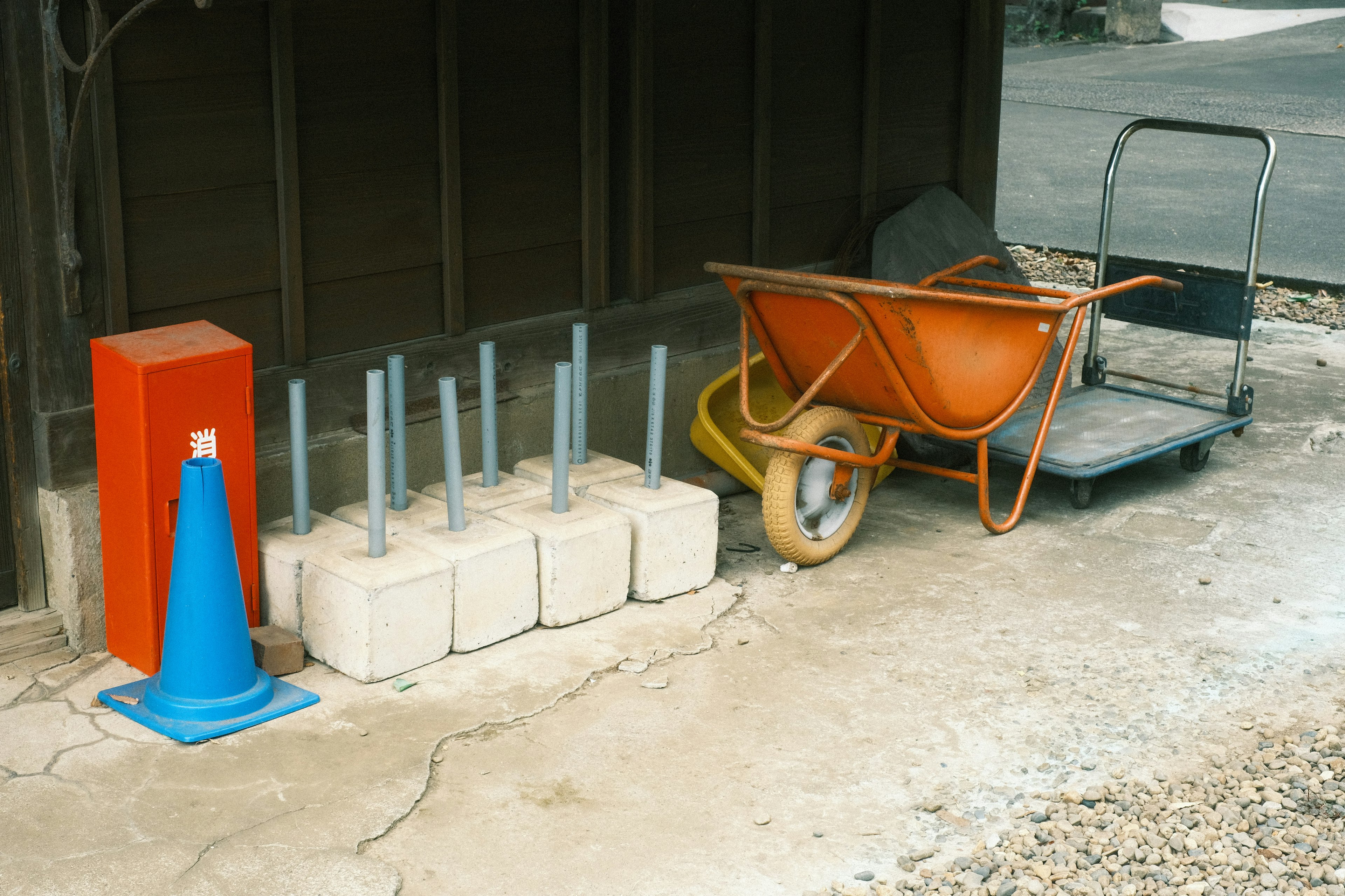 Construction tools including a blue cone and an orange wheelbarrow