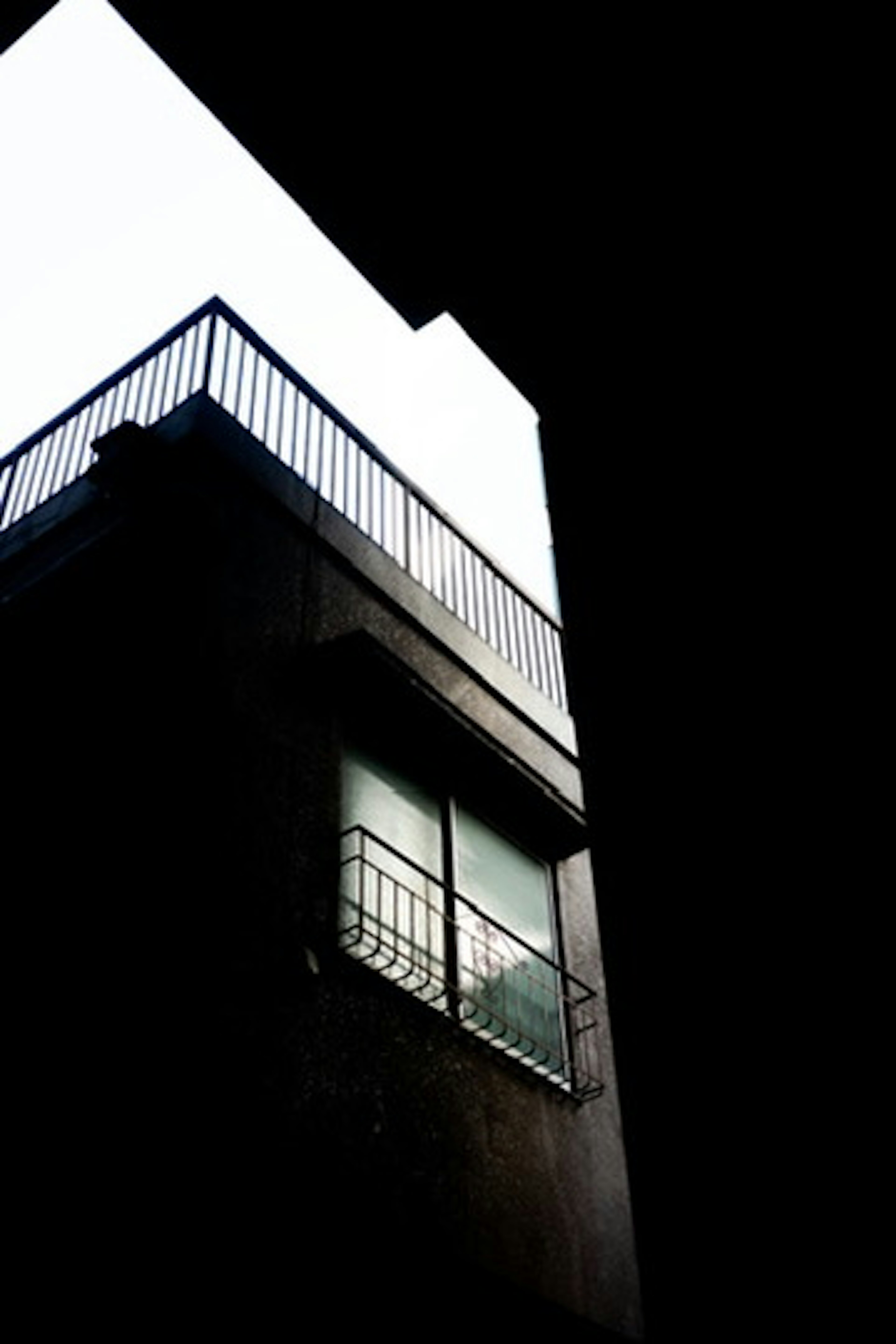 Building with balcony and window against a dark background