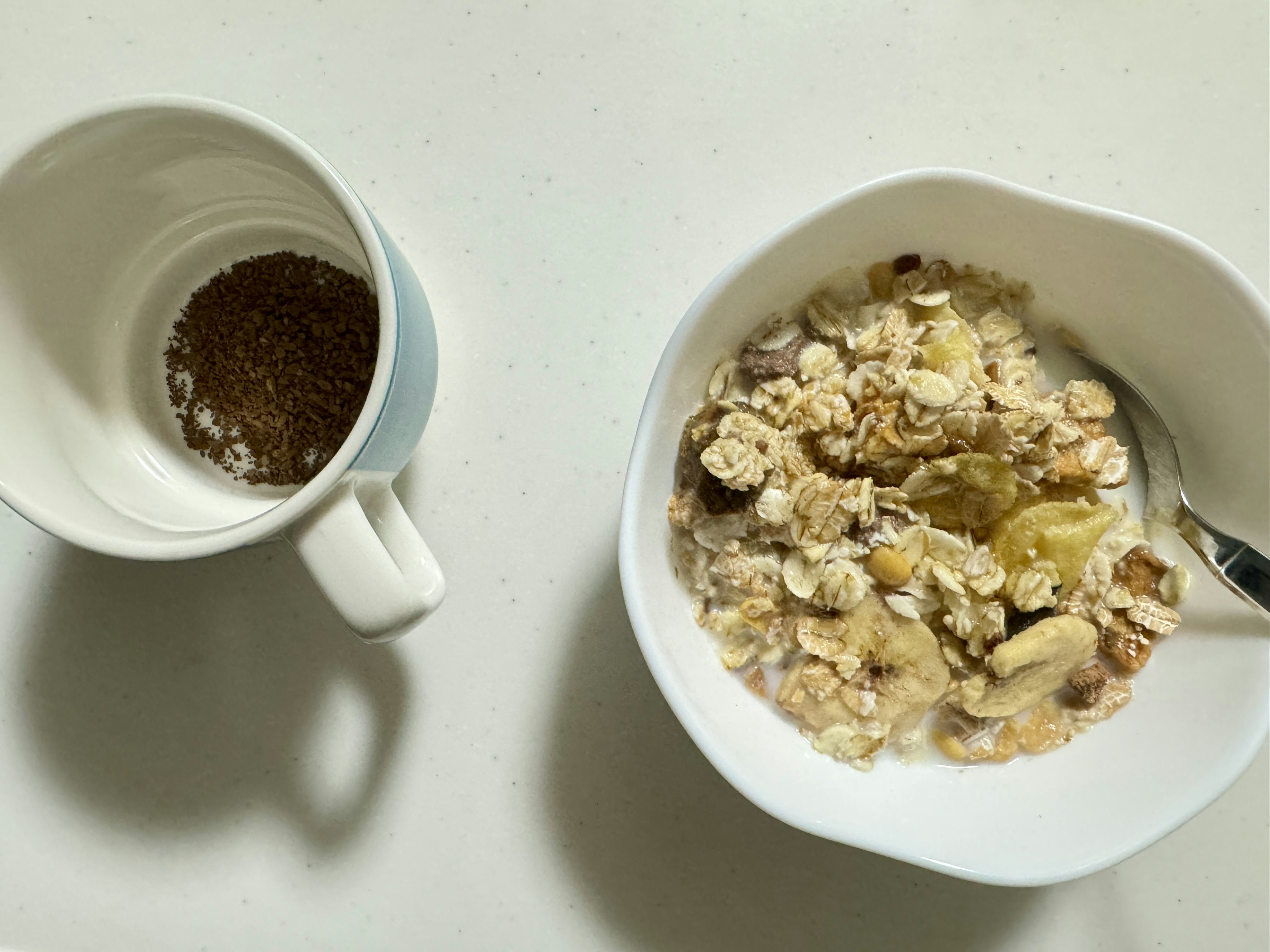 Tazón de avena con plátano y taza de café sobre una superficie blanca