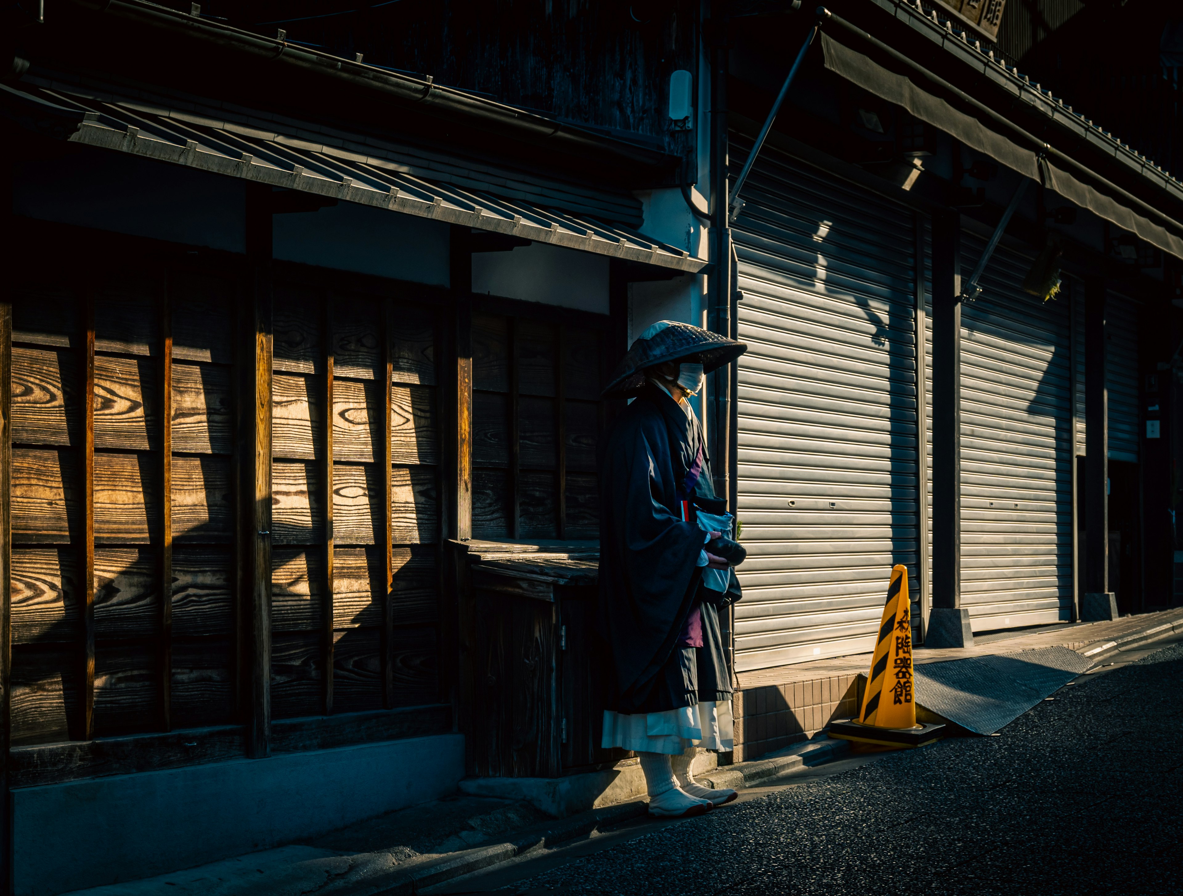 薄暗い通りに立つ女性の姿と木造の建物