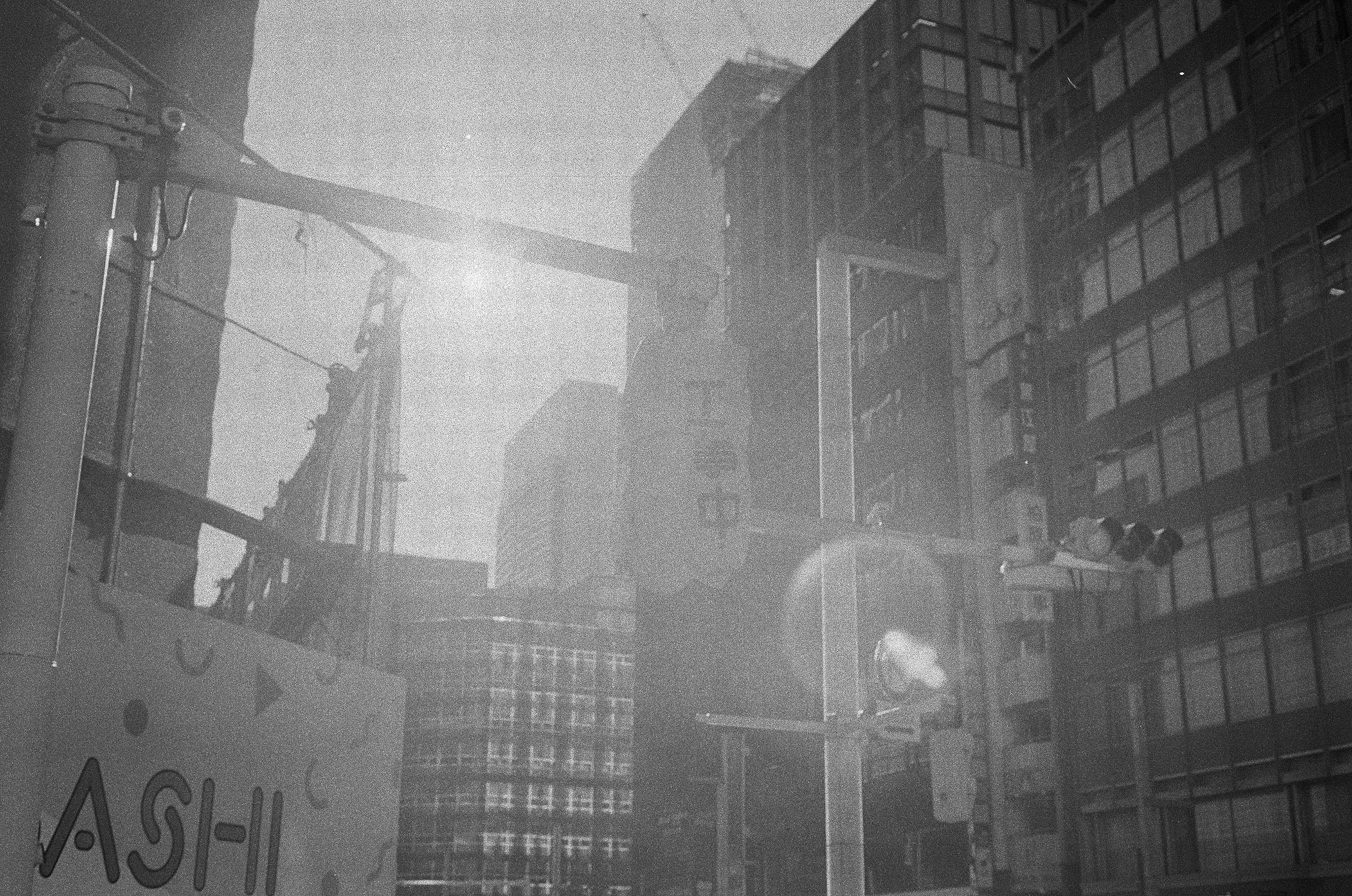 Black and white cityscape featuring skyscrapers and traffic lights with sunlight reflections