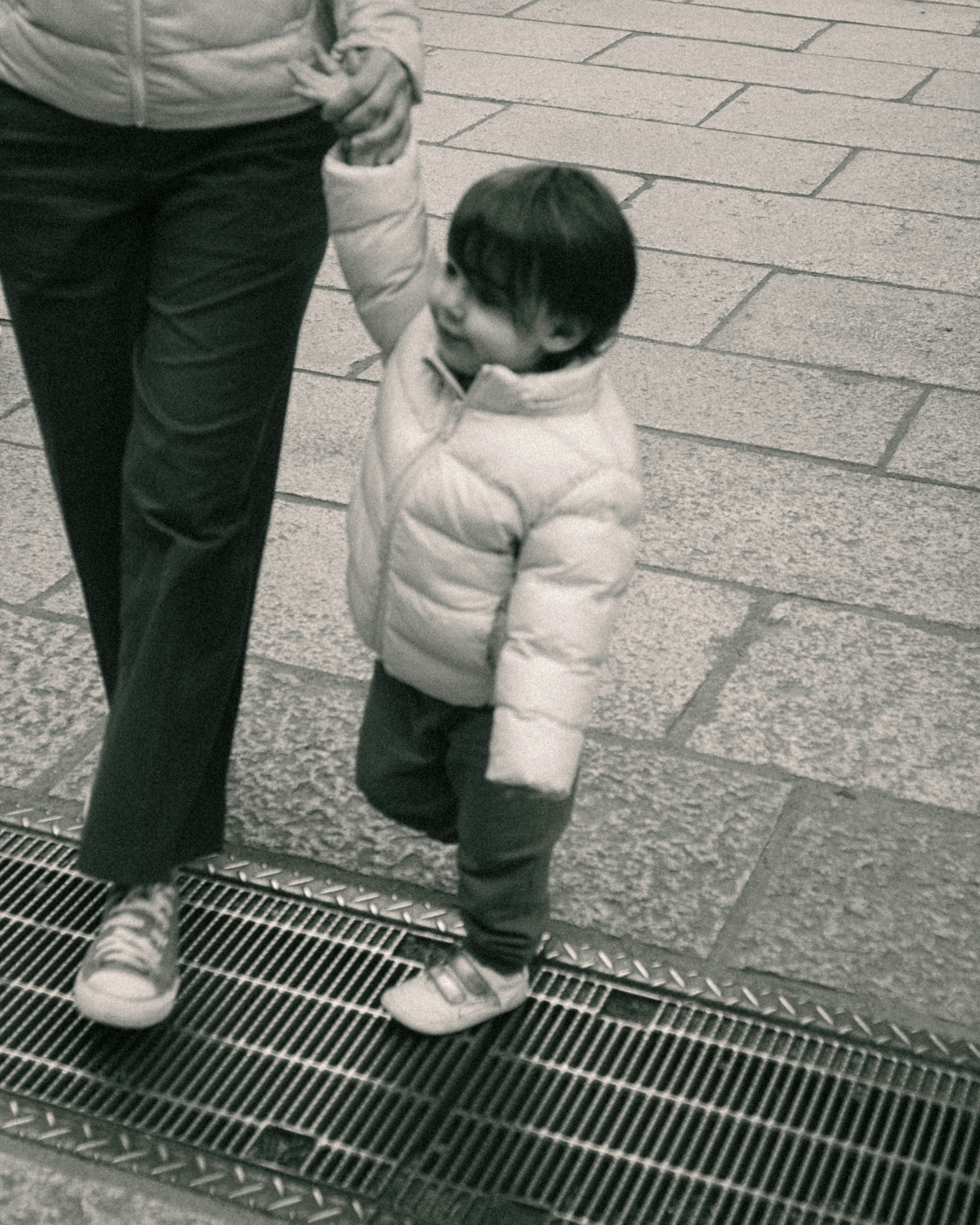 A child holding an adult's hand while walking in a monochrome photo