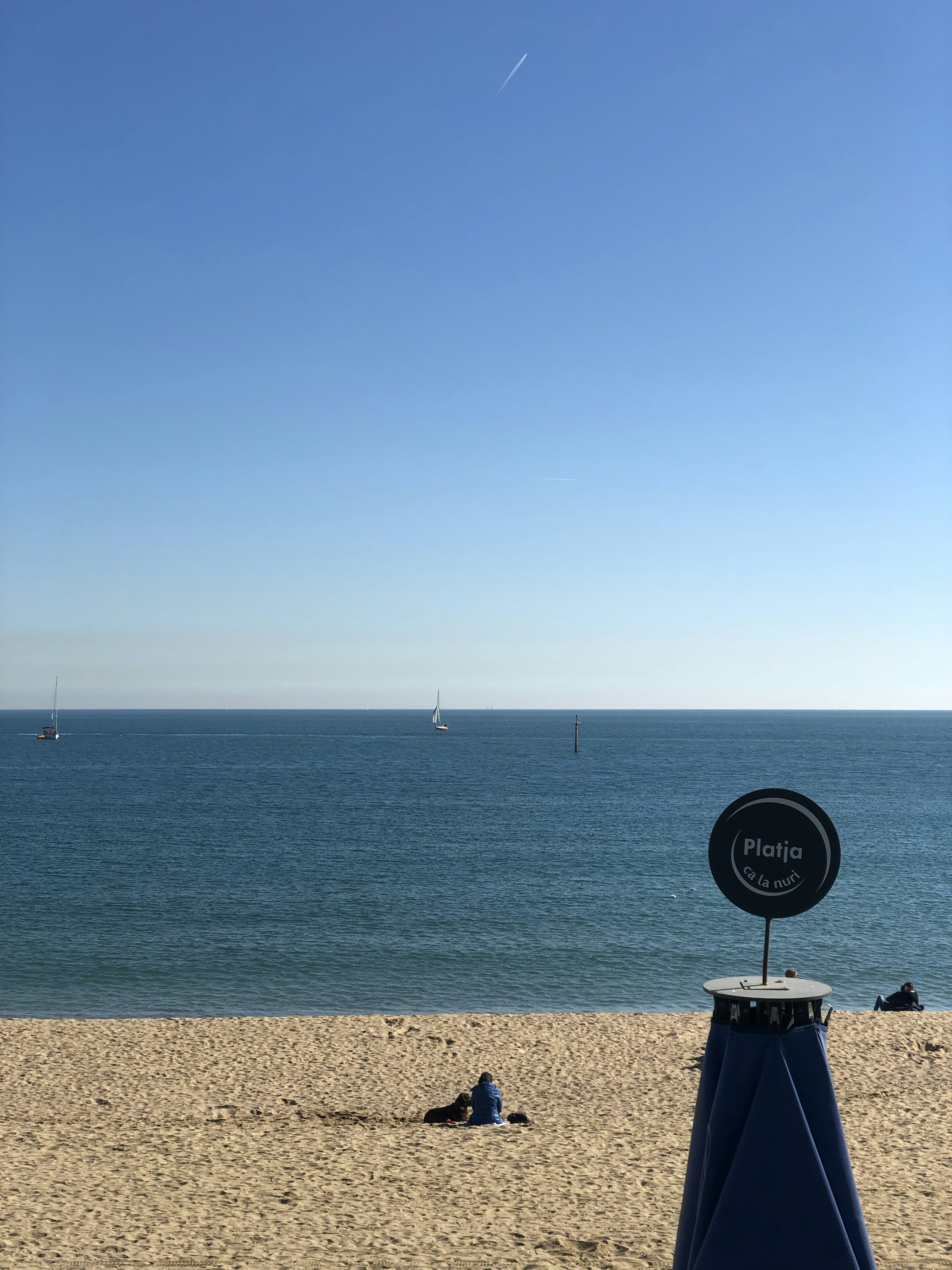 Scena di spiaggia con mare blu sotto un cielo sereno con una persona sdraiata