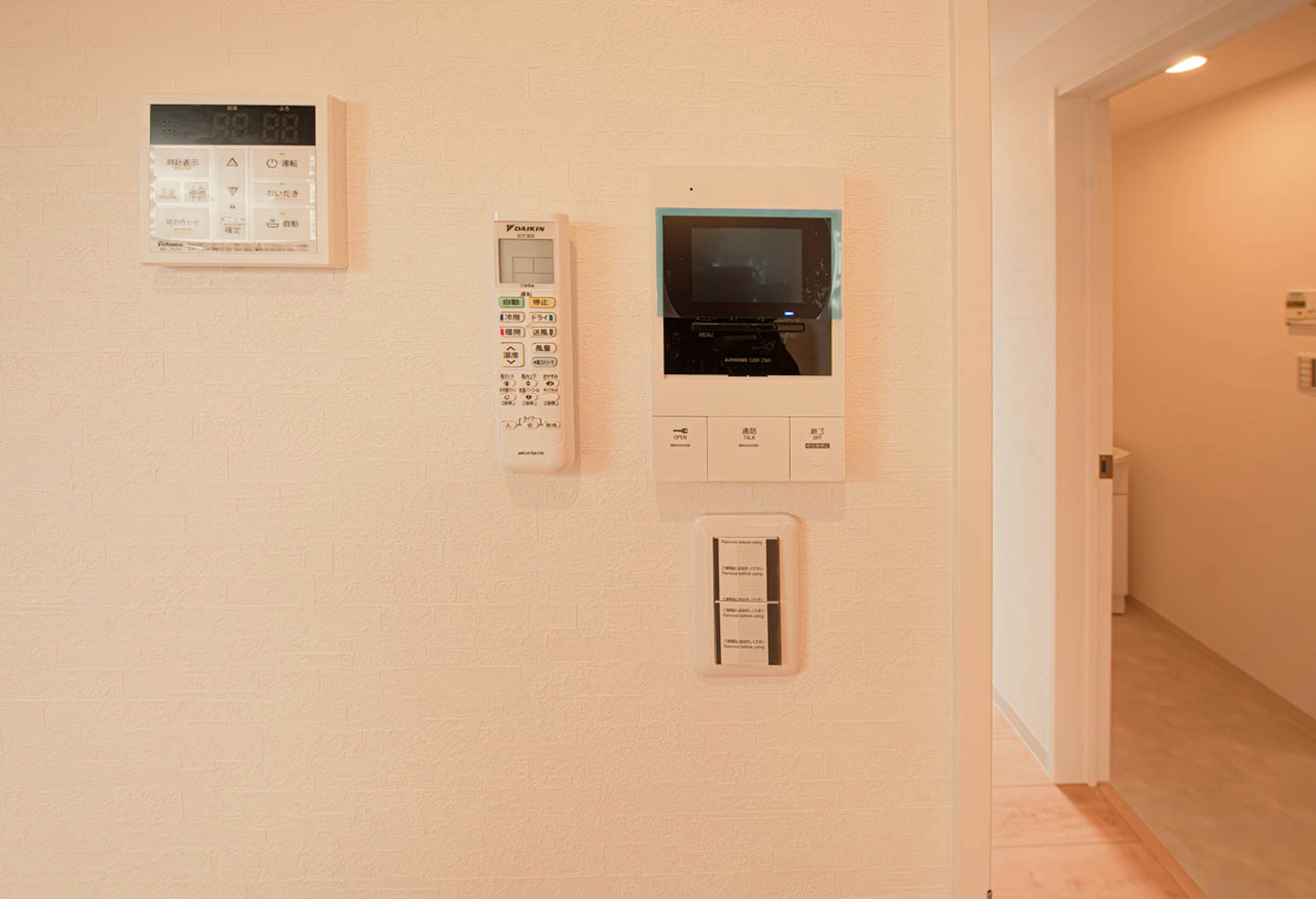 Interior of a room with a monitor and remote control mounted on a white wall