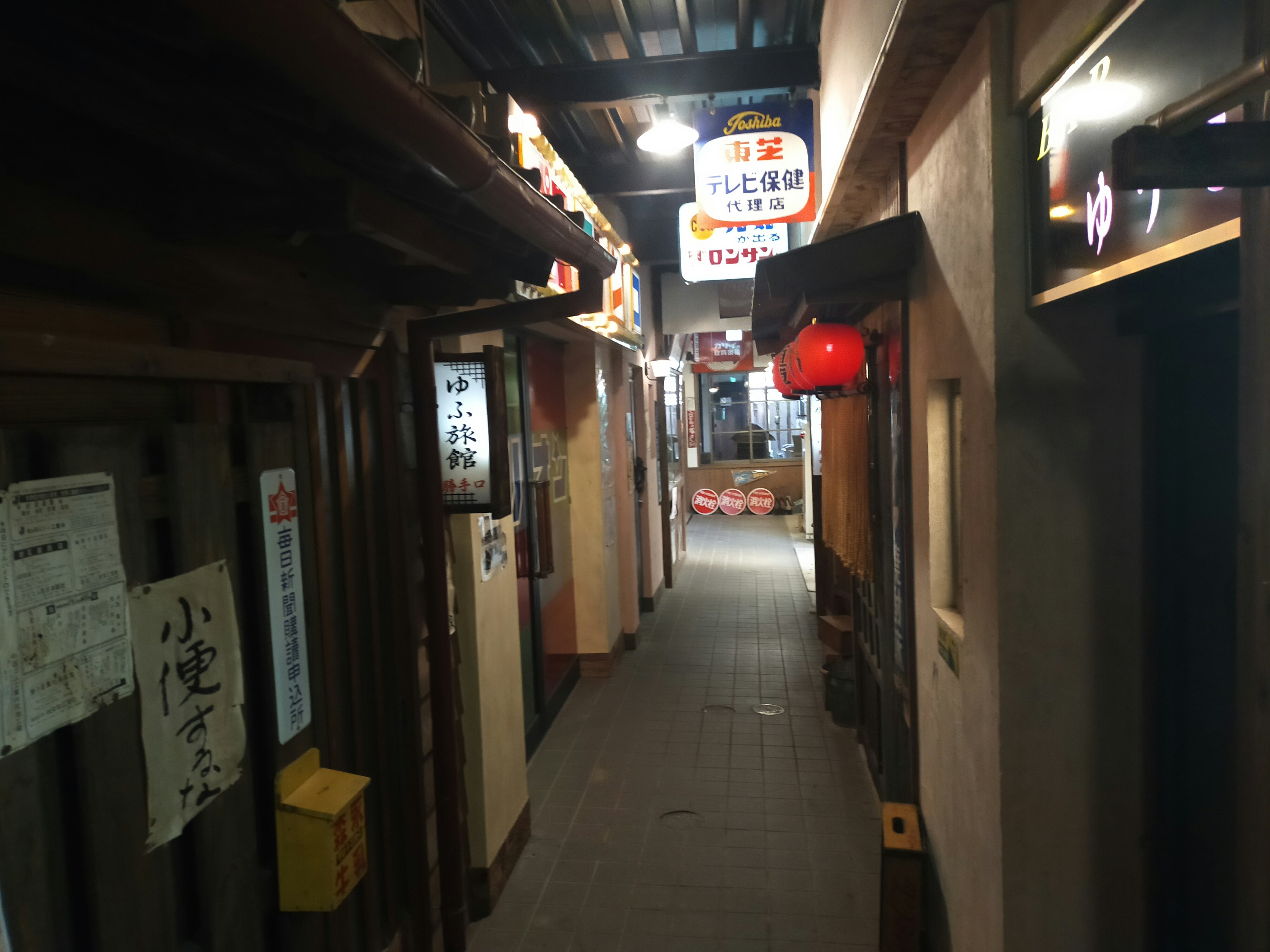 Narrow alley with traditional Japanese izakaya entrances and hanging lanterns