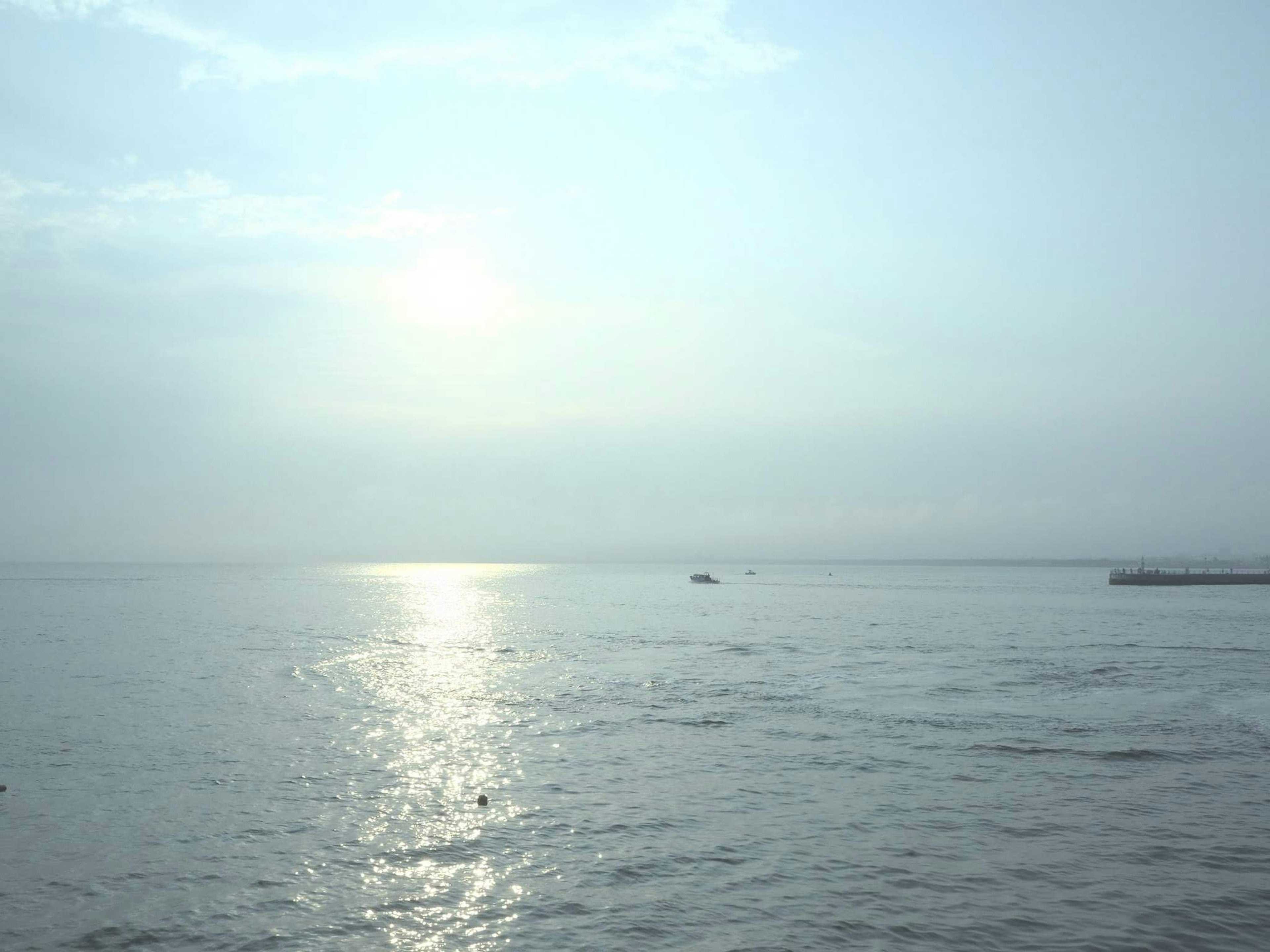 Calm sea reflecting light and soft clouds