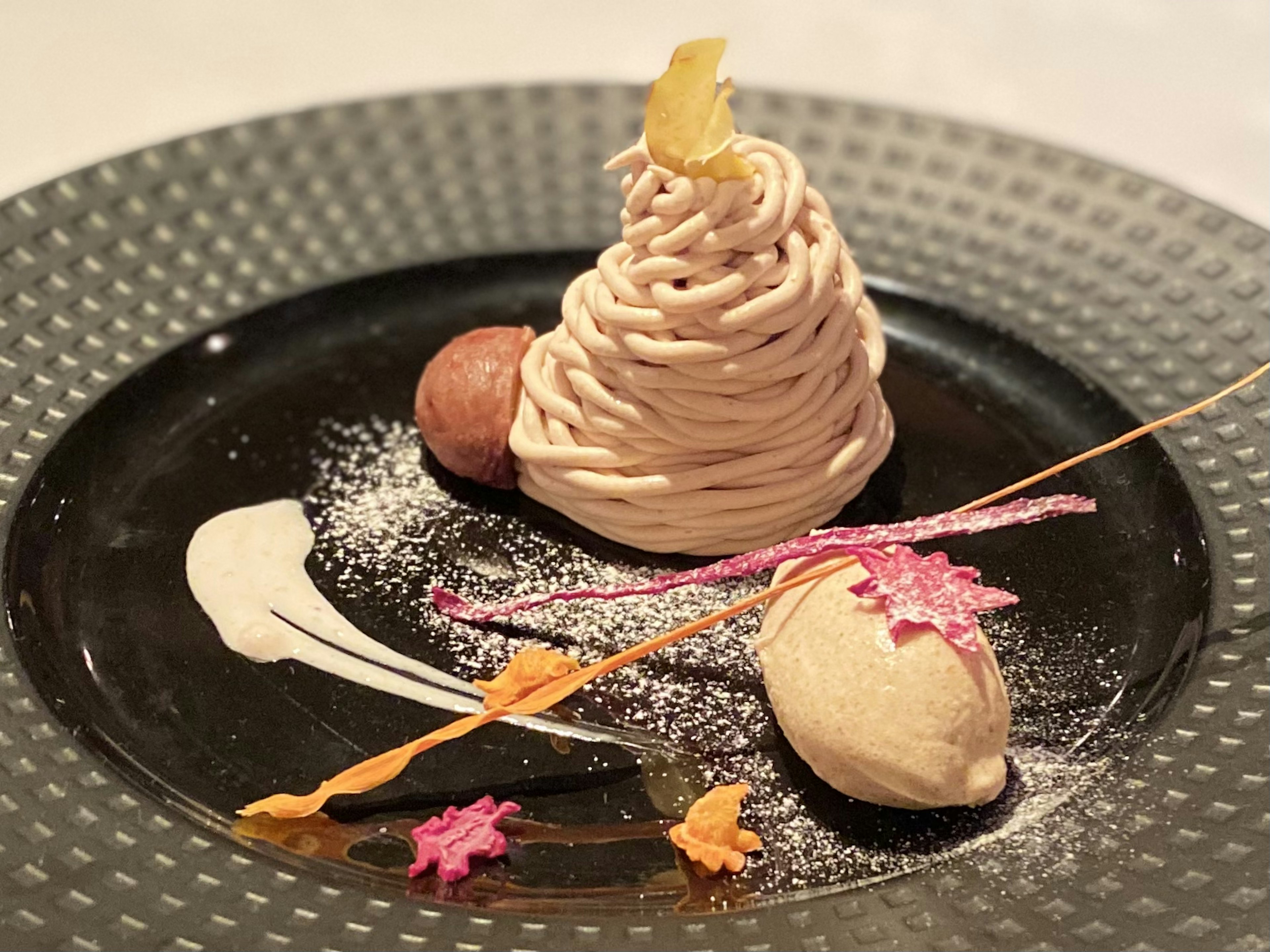 Piatto di dessert elegante con mont blanc e gelato decorato con guarnizioni colorate