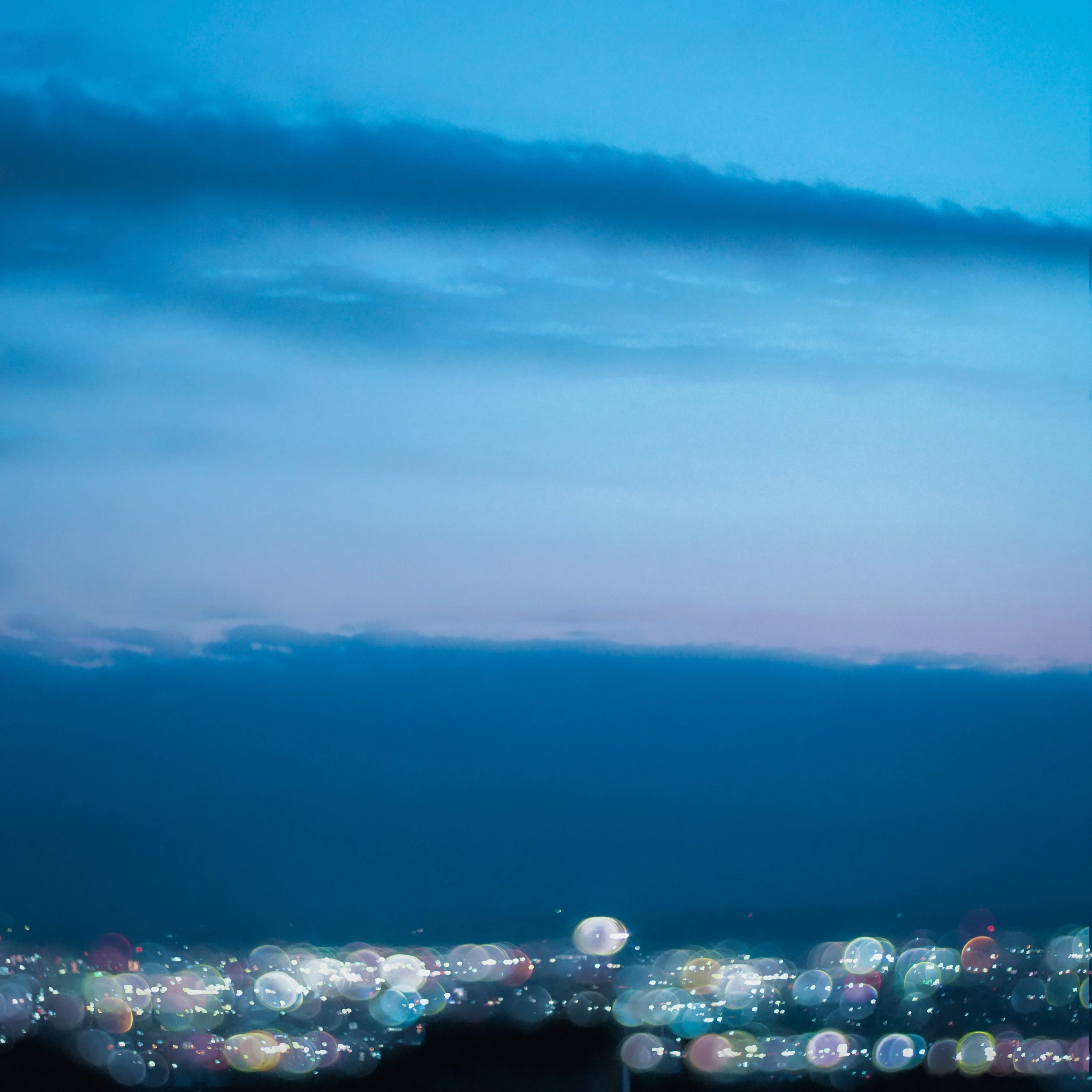 Paisaje urbano nocturno con cielo azul y luces de la ciudad borrosas