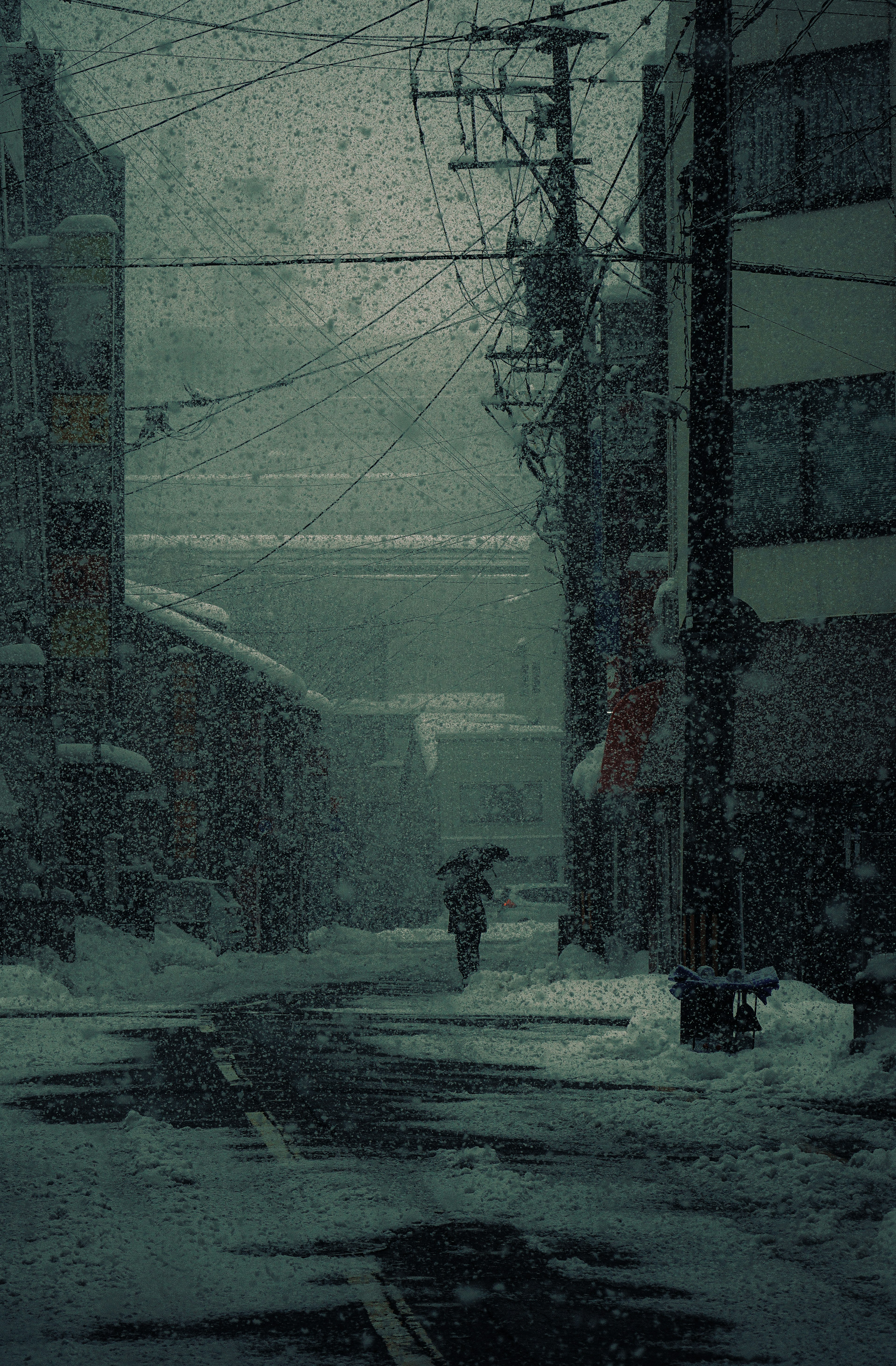 A person walking with an umbrella in a dark snowy street scene