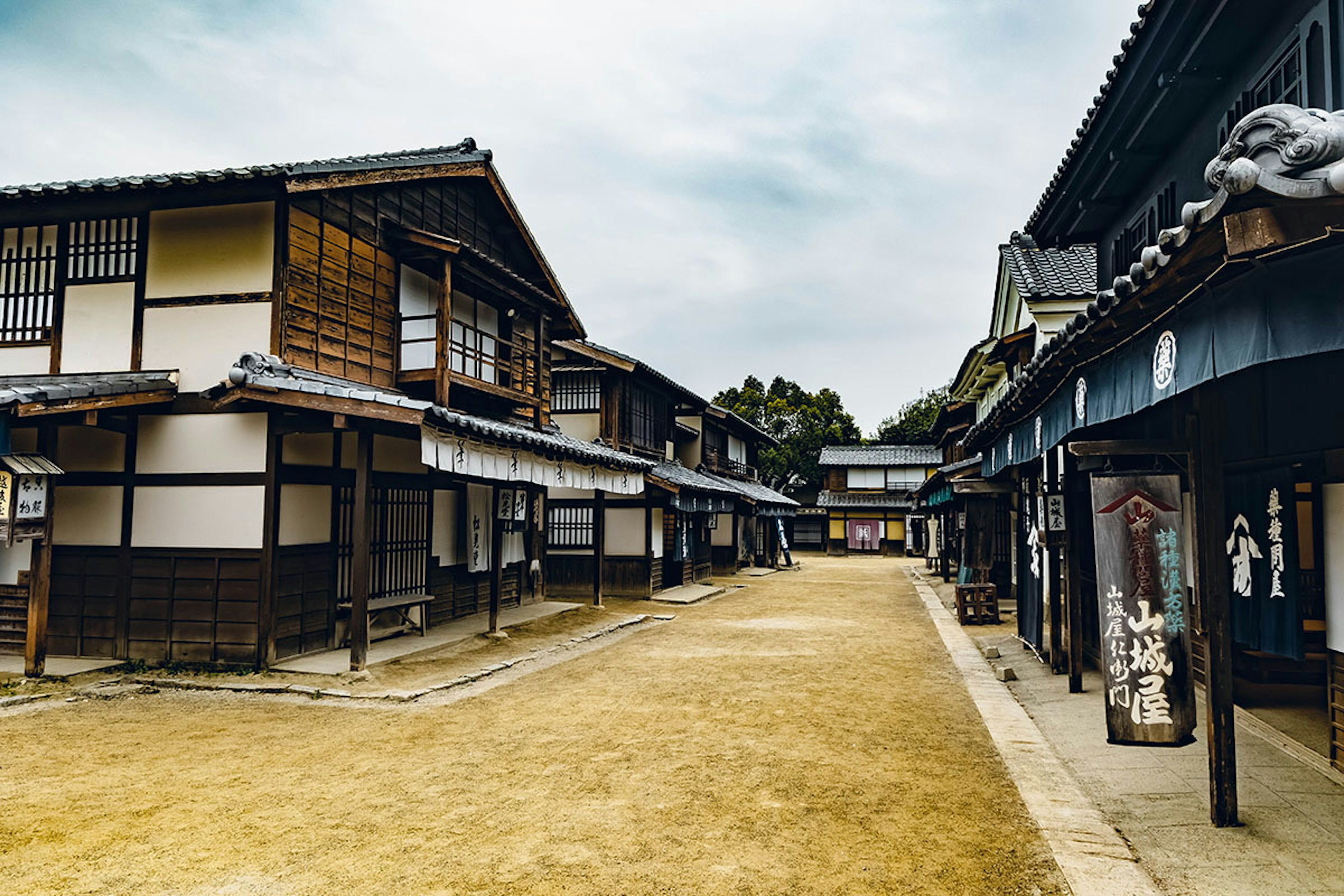 Scène de rue japonaise traditionnelle avec des bâtiments en bois et un ciel nuageux