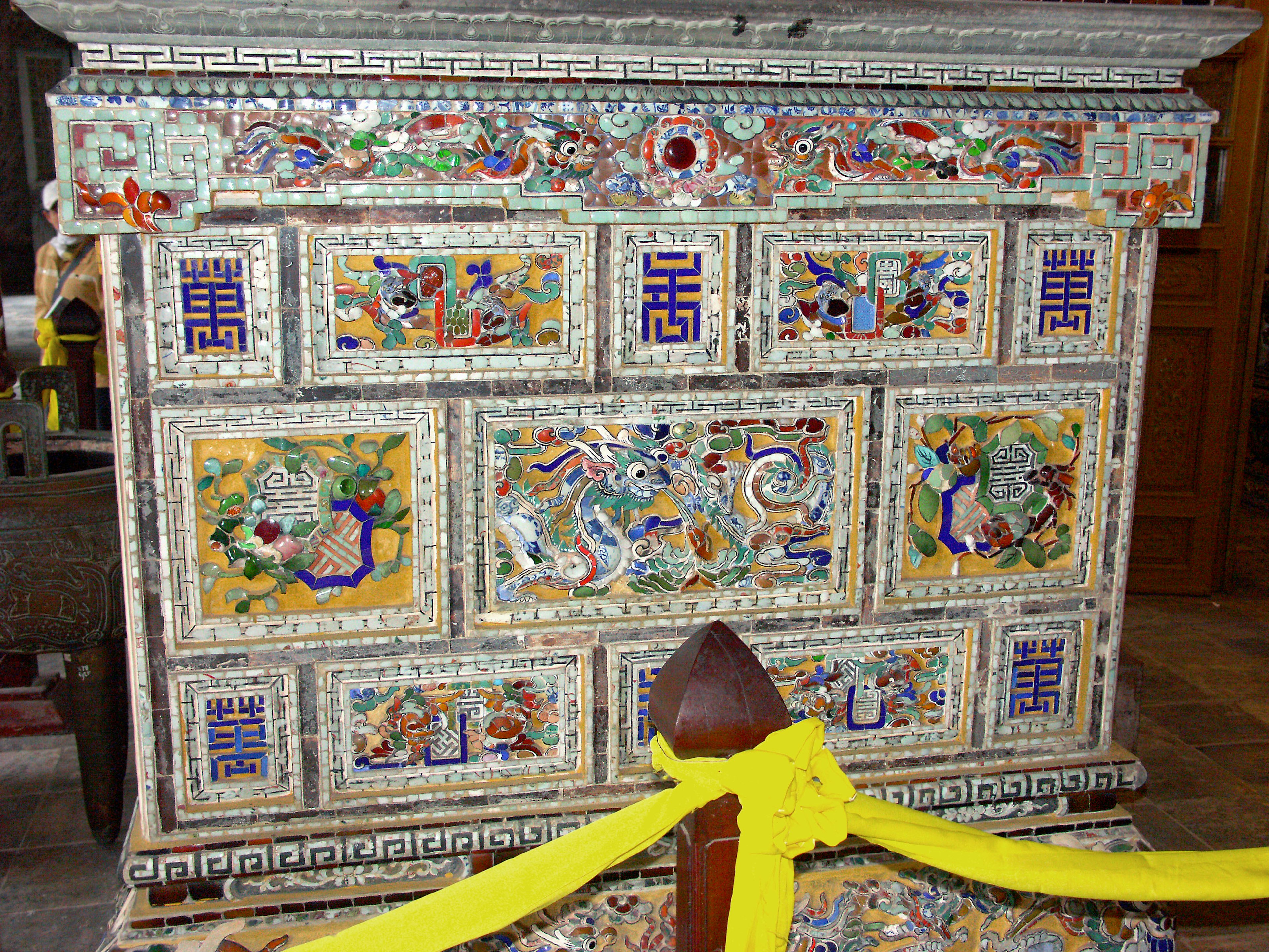 Traditional wooden cabinet with vibrant decorations and colorful motifs yellow ribbon displayed in front