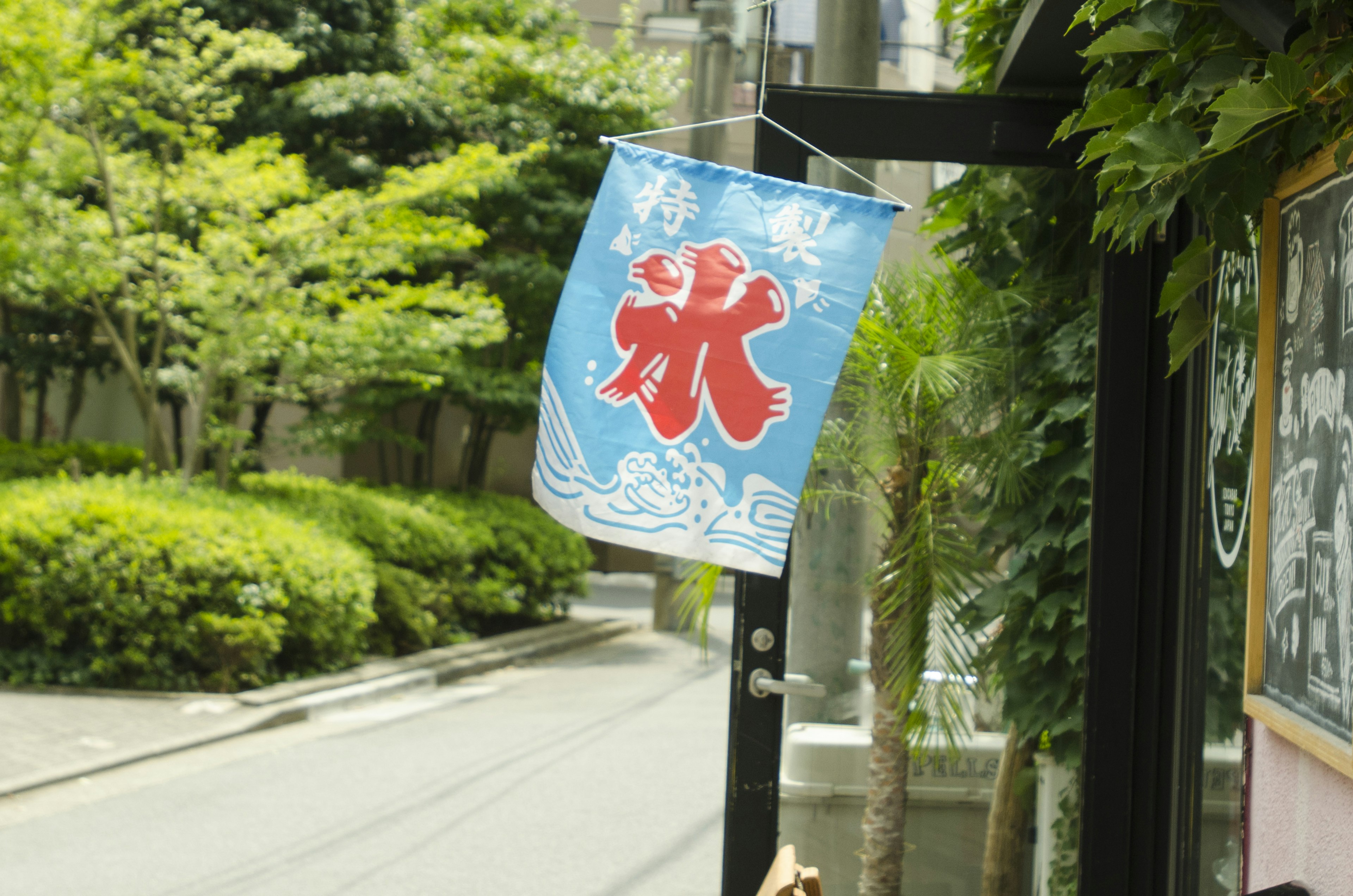 Bandiera blu con carattere kanji rosso per il ghiaccio esposta all'esterno di un negozio