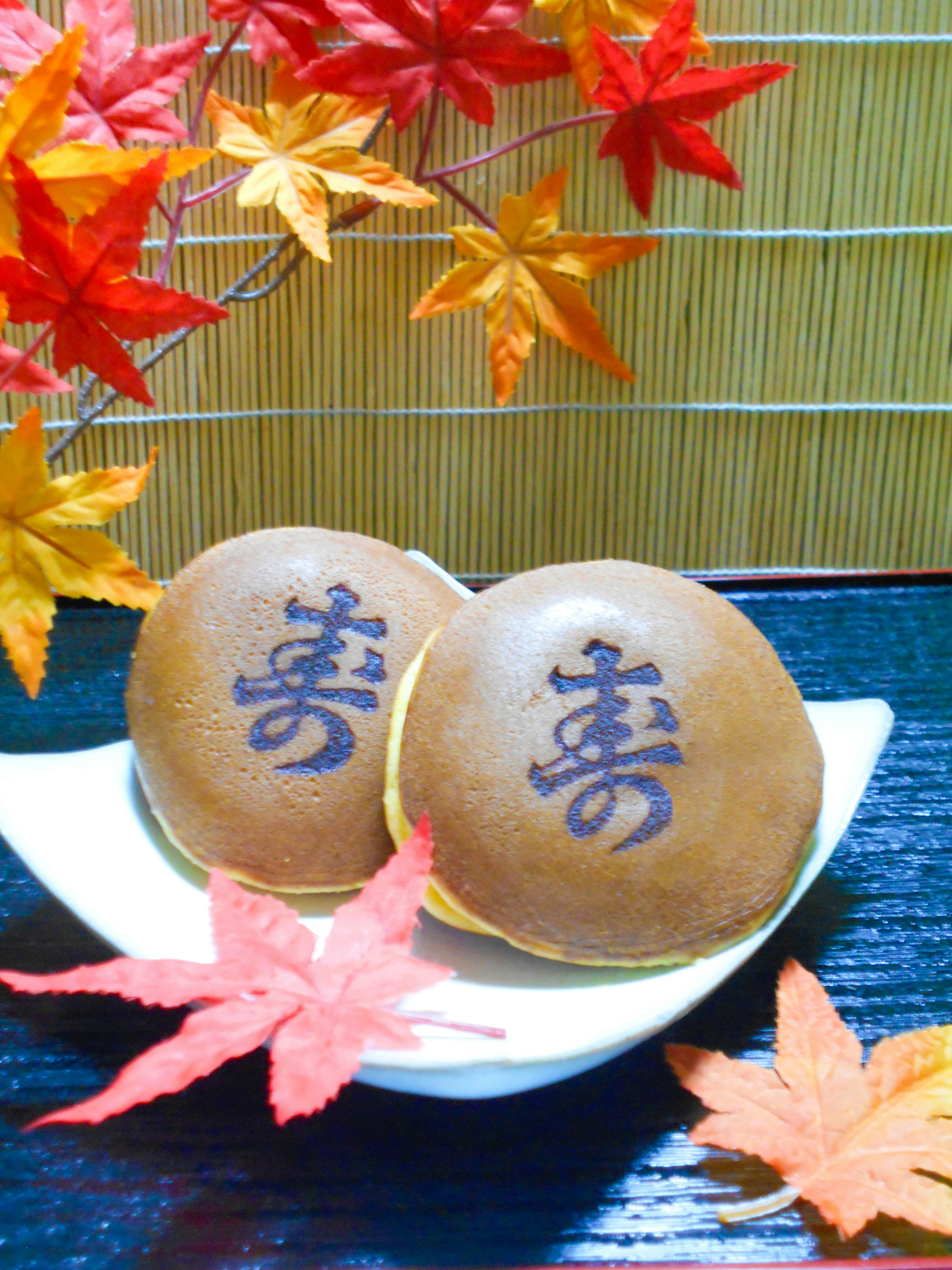 Deux petits pains japonais présentés avec des feuilles d'automne et des caractères kanji imprimés